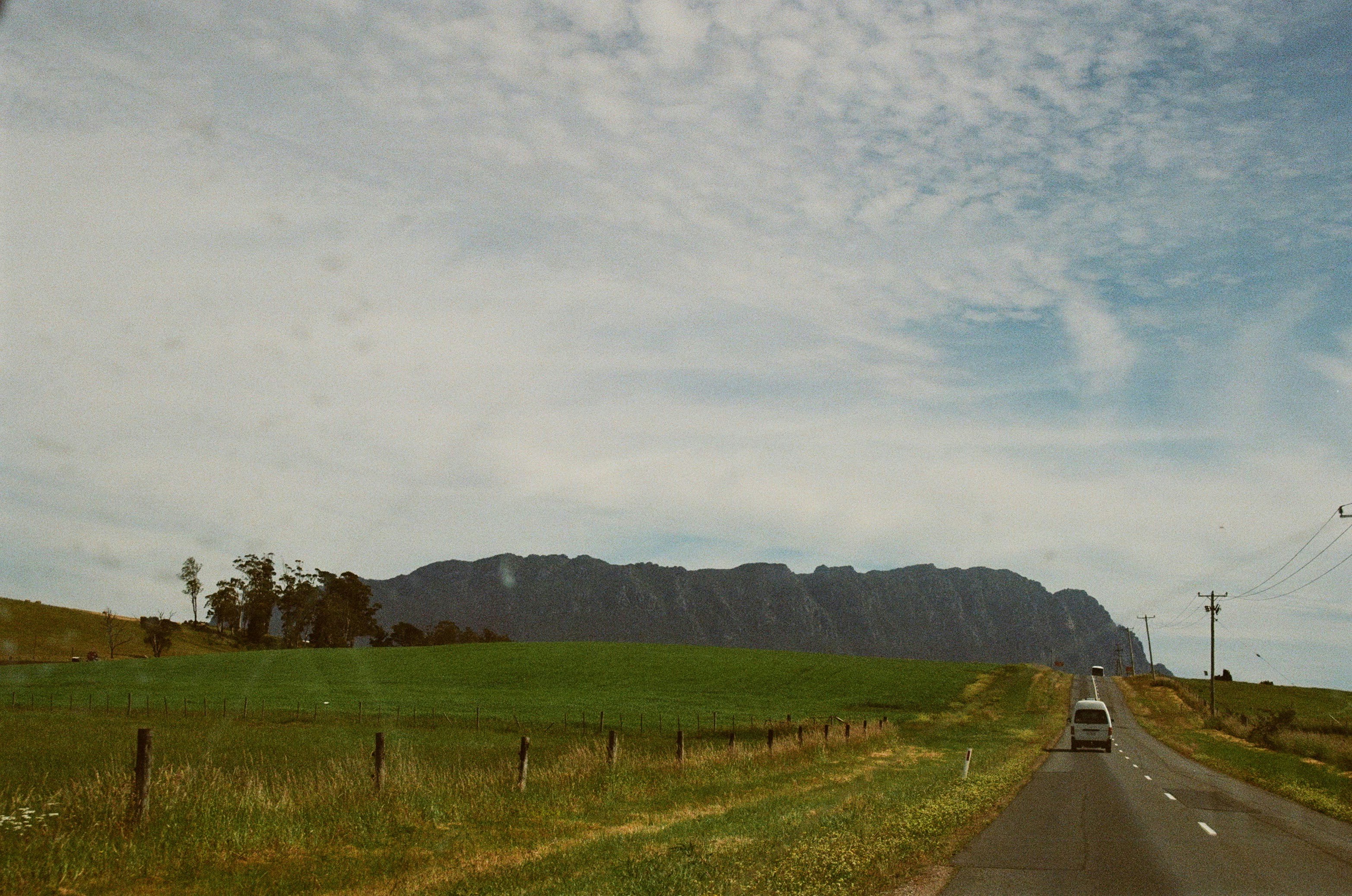 Van driving on road towards distant mountain range.