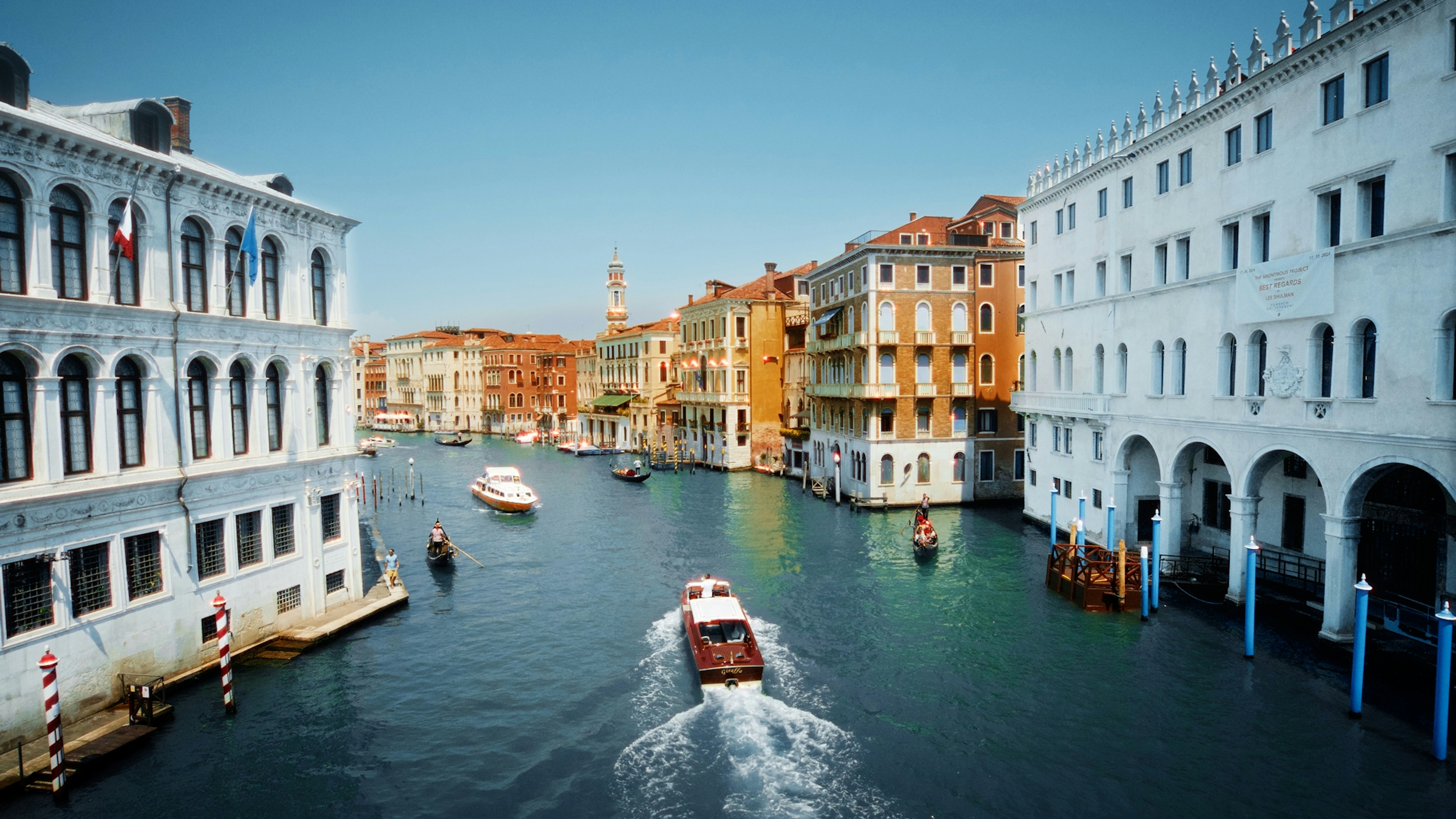 Barcos navegan por un canal bordeado de edificios históricos en Venecia.