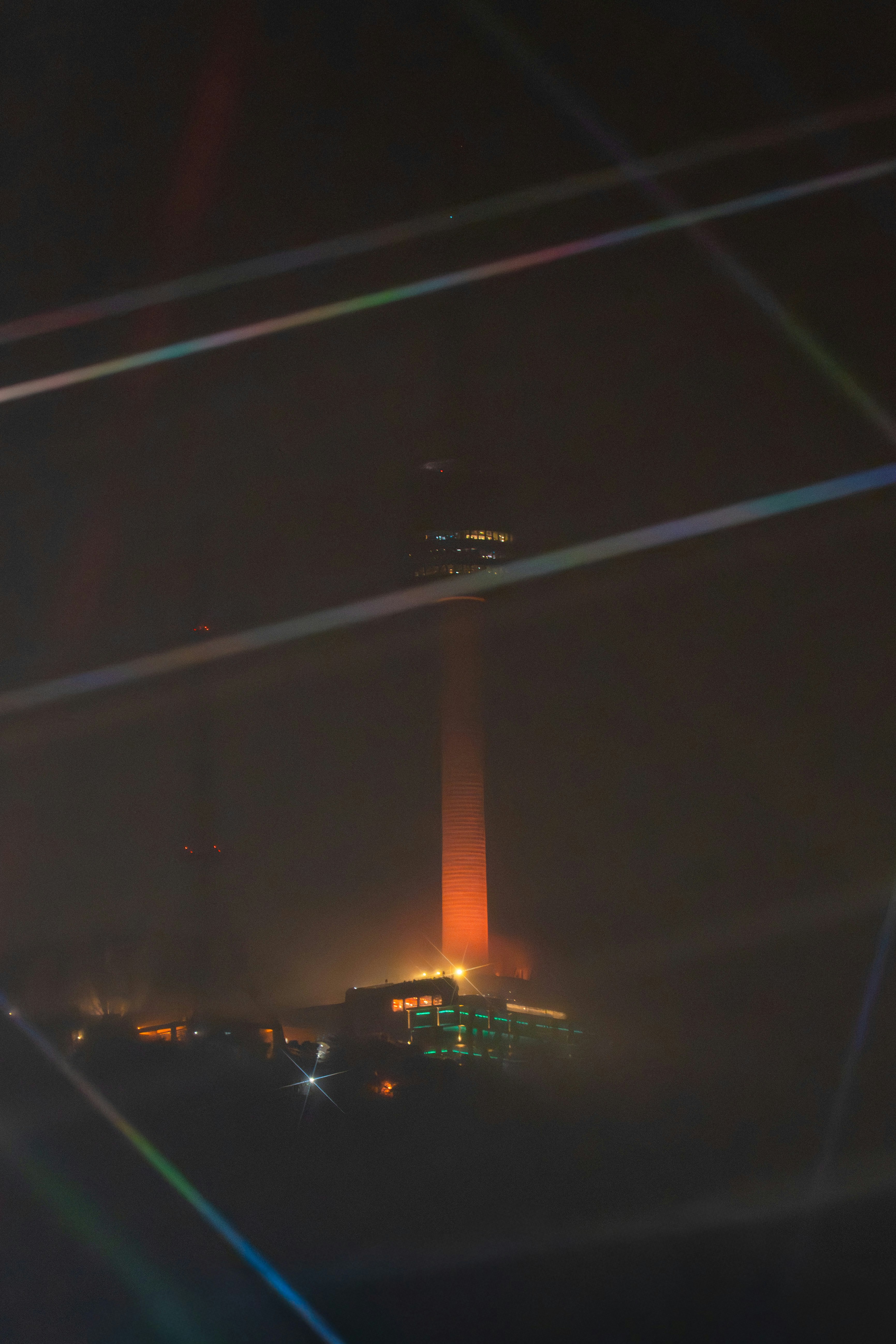 Tall tower illuminated at night with colorful light streaks.
