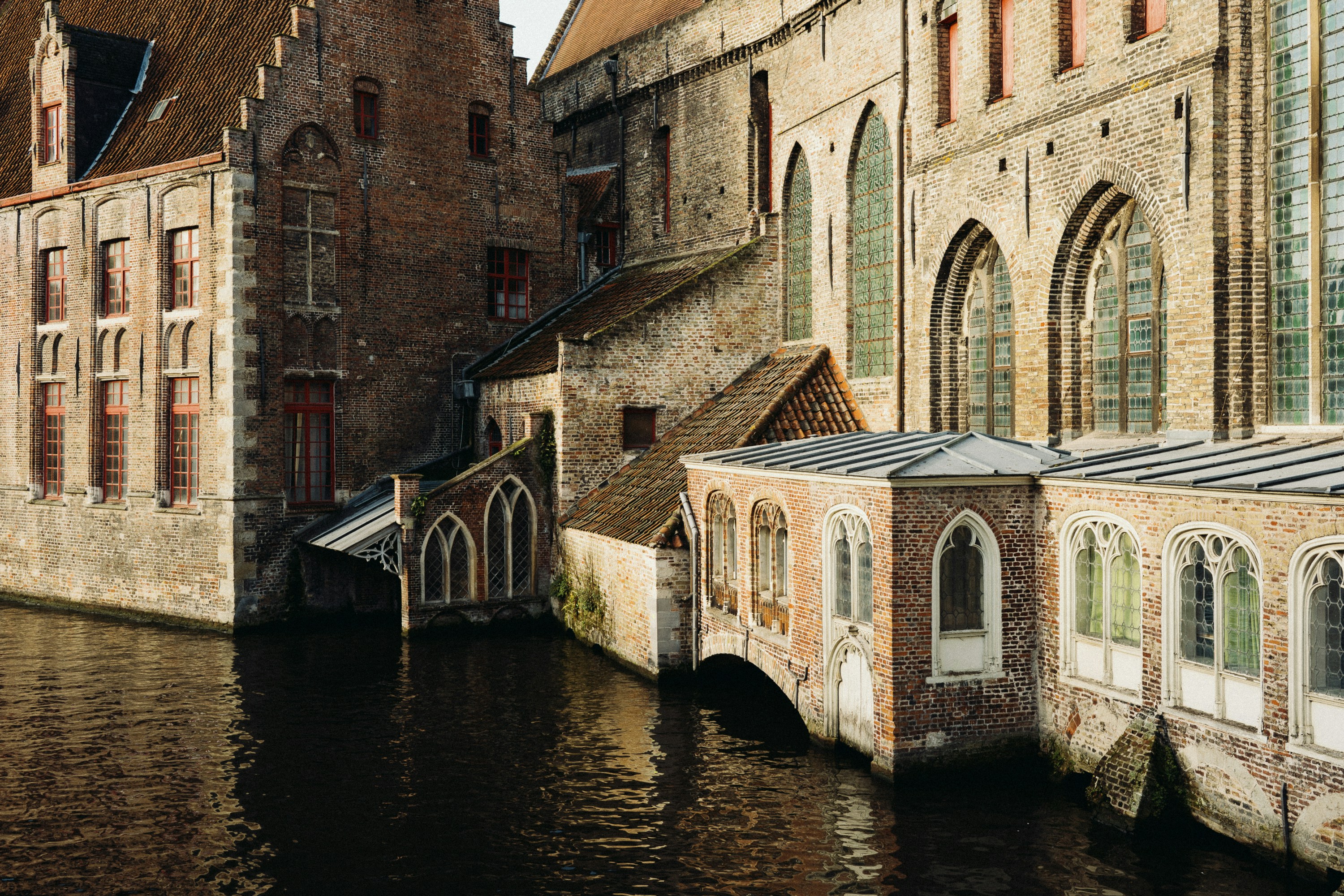 Historic buildings line a calm canal in bruges.