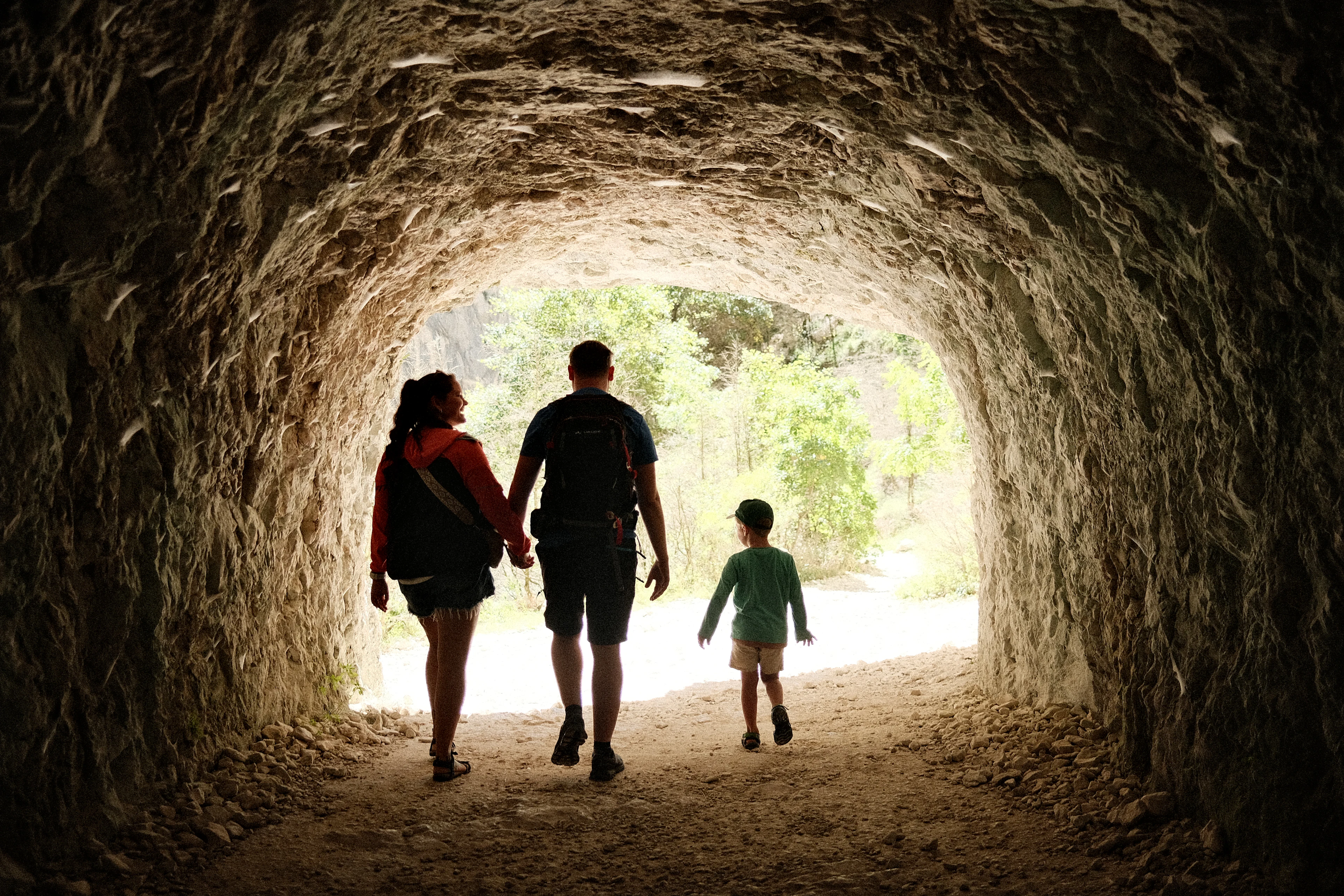A family walking through a stone tunnel towards the light