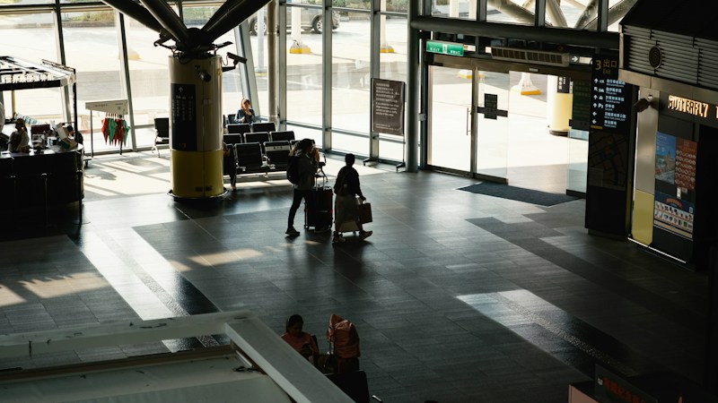 Travelers with rolling luggage walking through a modern airport terminal, like locals heading out of Harry Reid for the holidays