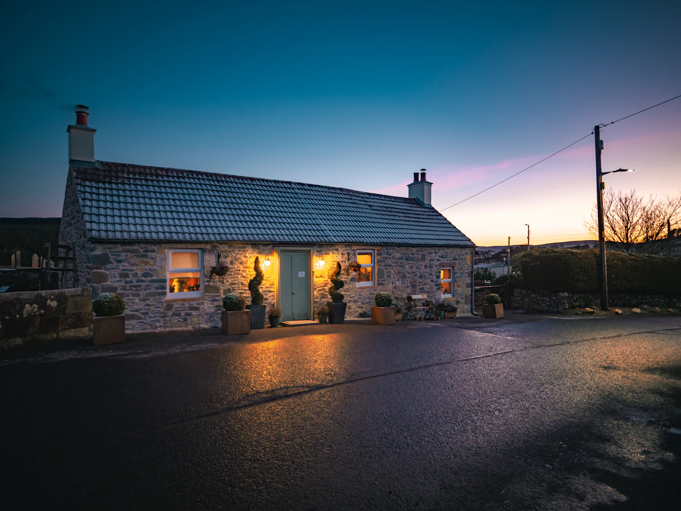 Stone cottage with lit windows at dusk