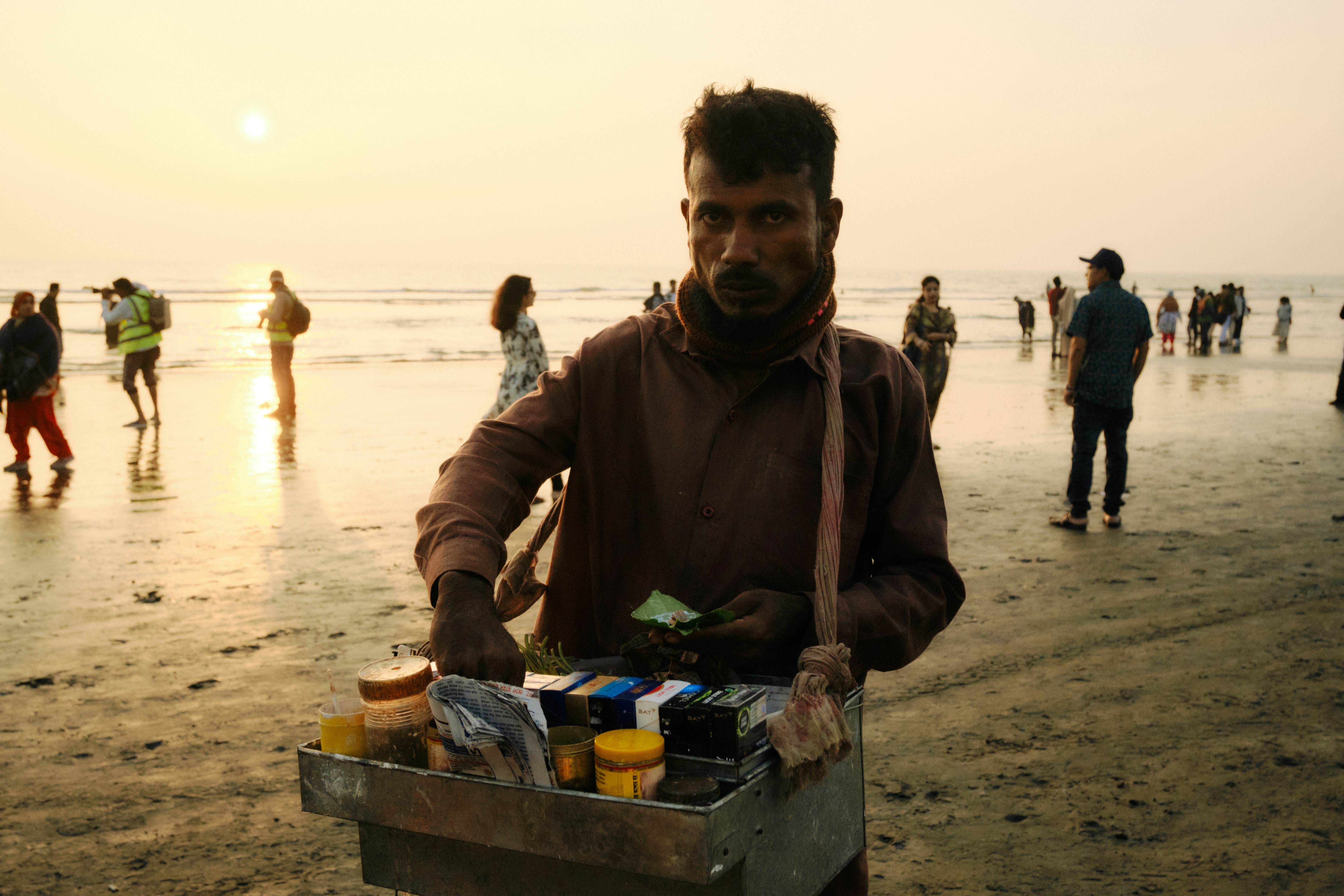 Homem vendendo mercadorias em uma praia ao pôr do sol
