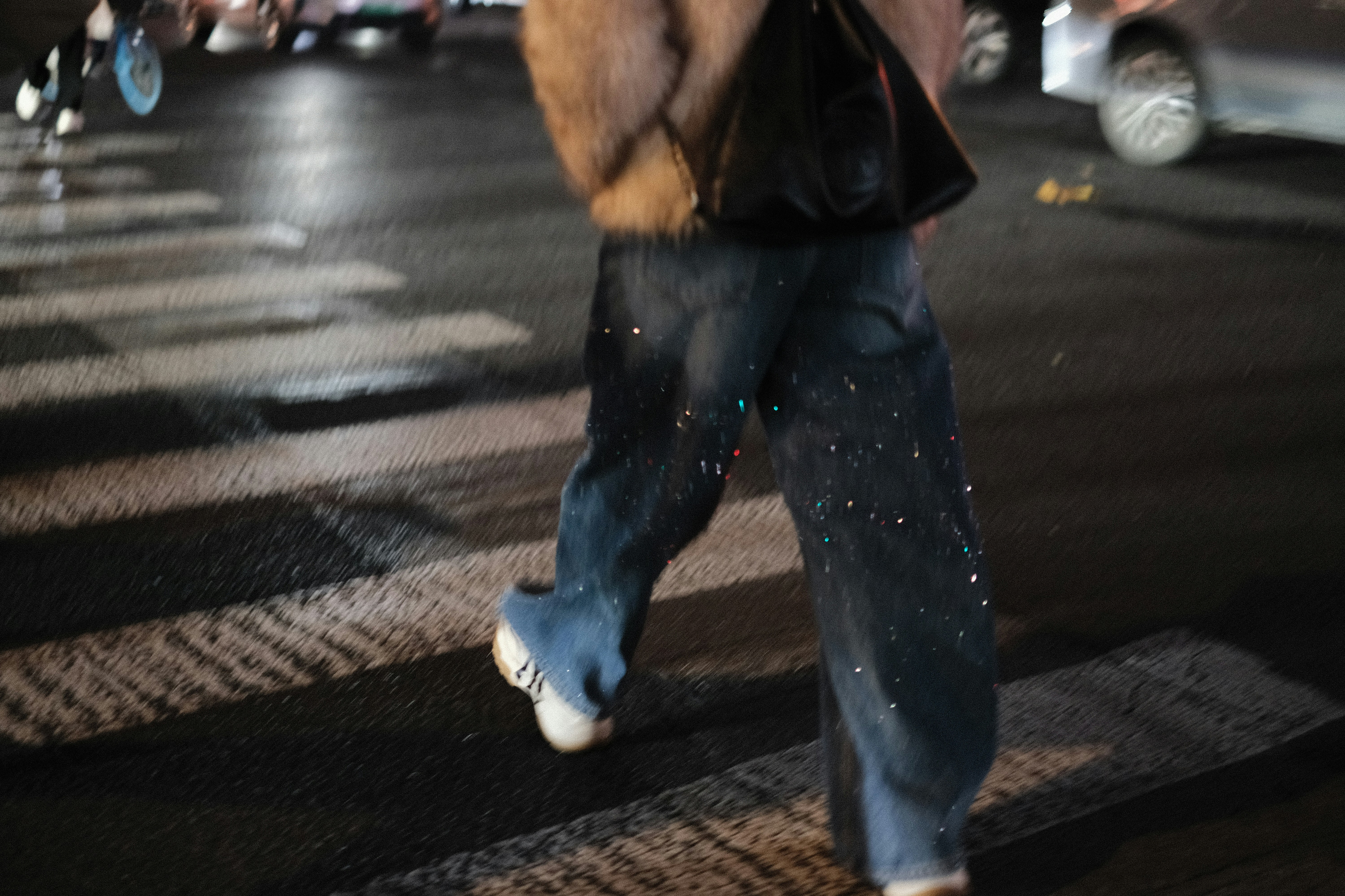 Person crossing a wet street at night
