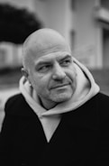 Bald man with beard wearing coat and hoodie