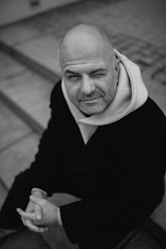 Bald man winks while looking up from steps.