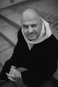 Bald man winks while looking up from steps.