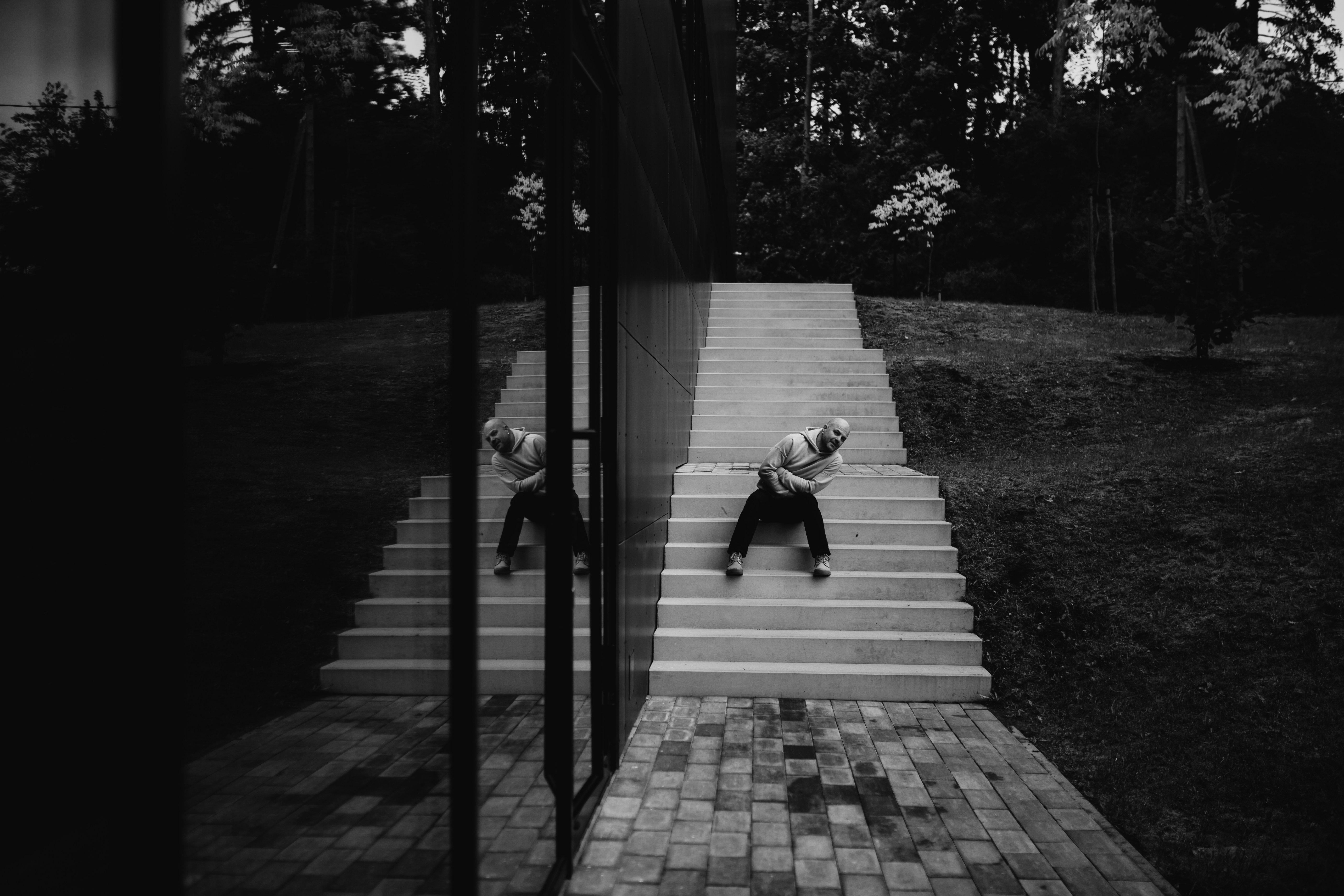 Man walking down outdoor stairs reflected in glass