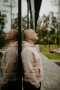 Bald man in hoodie leans against glass building