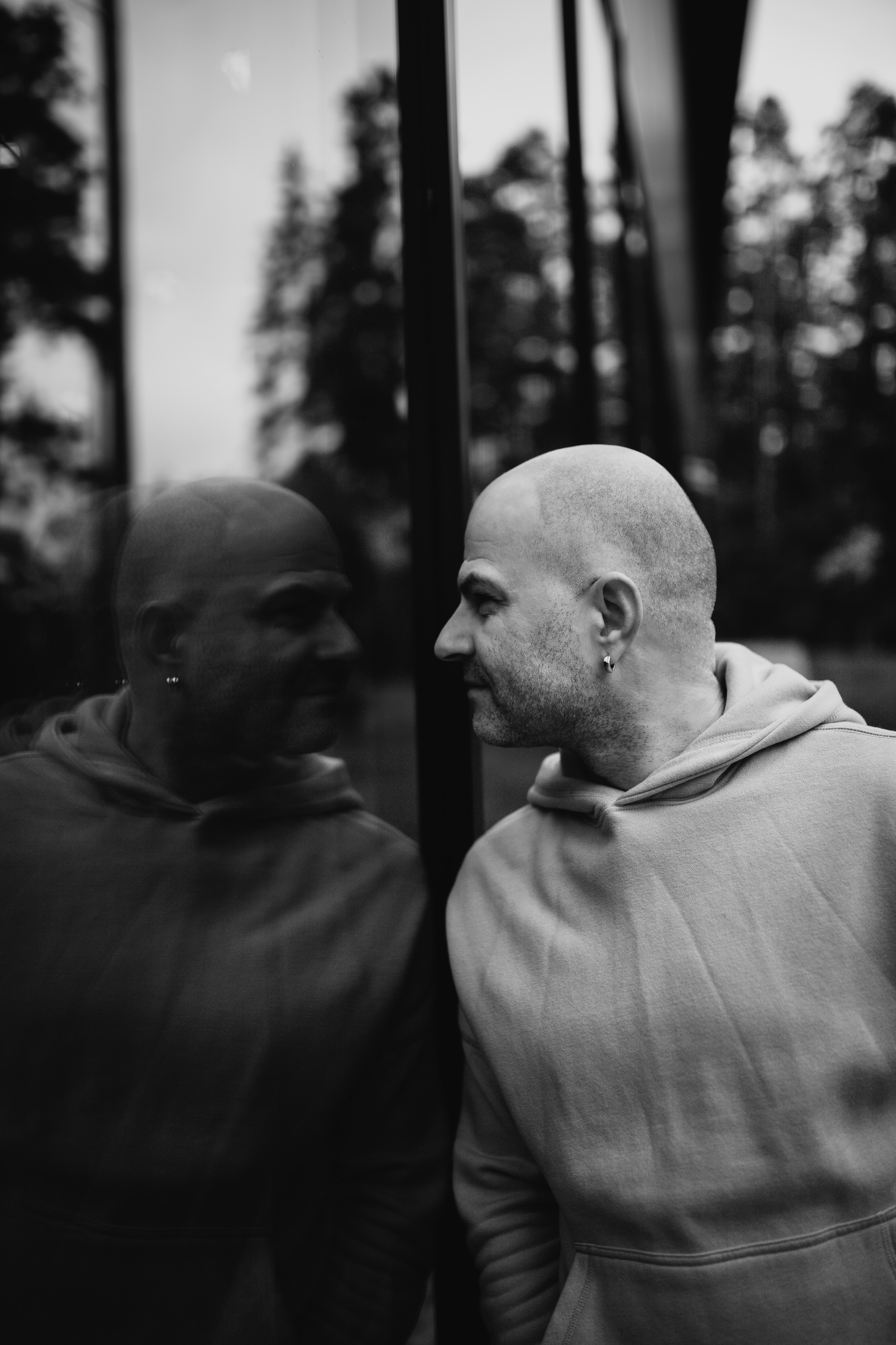 Bald man in hoodie looks at his reflection
