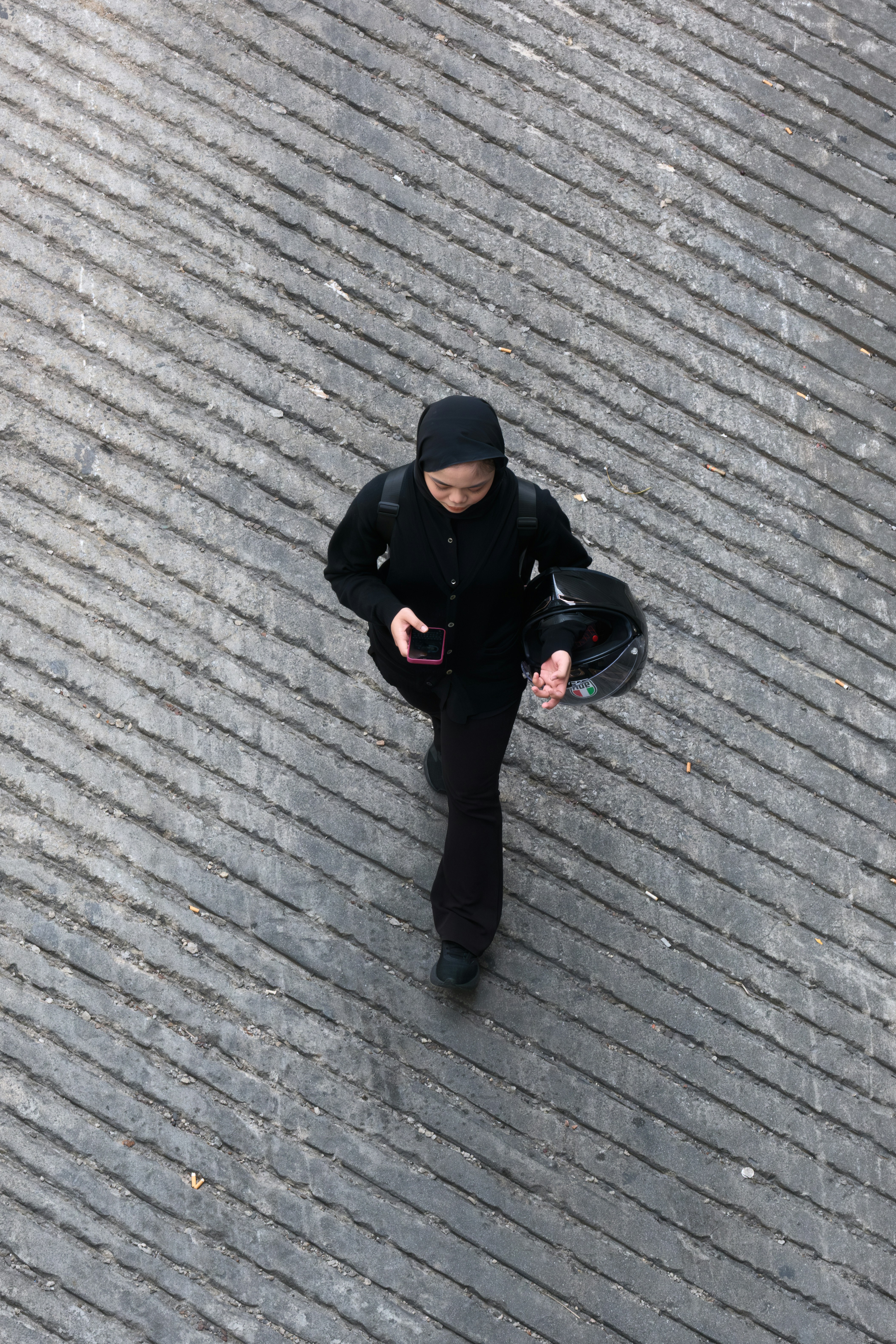 Person in black walks on textured ground