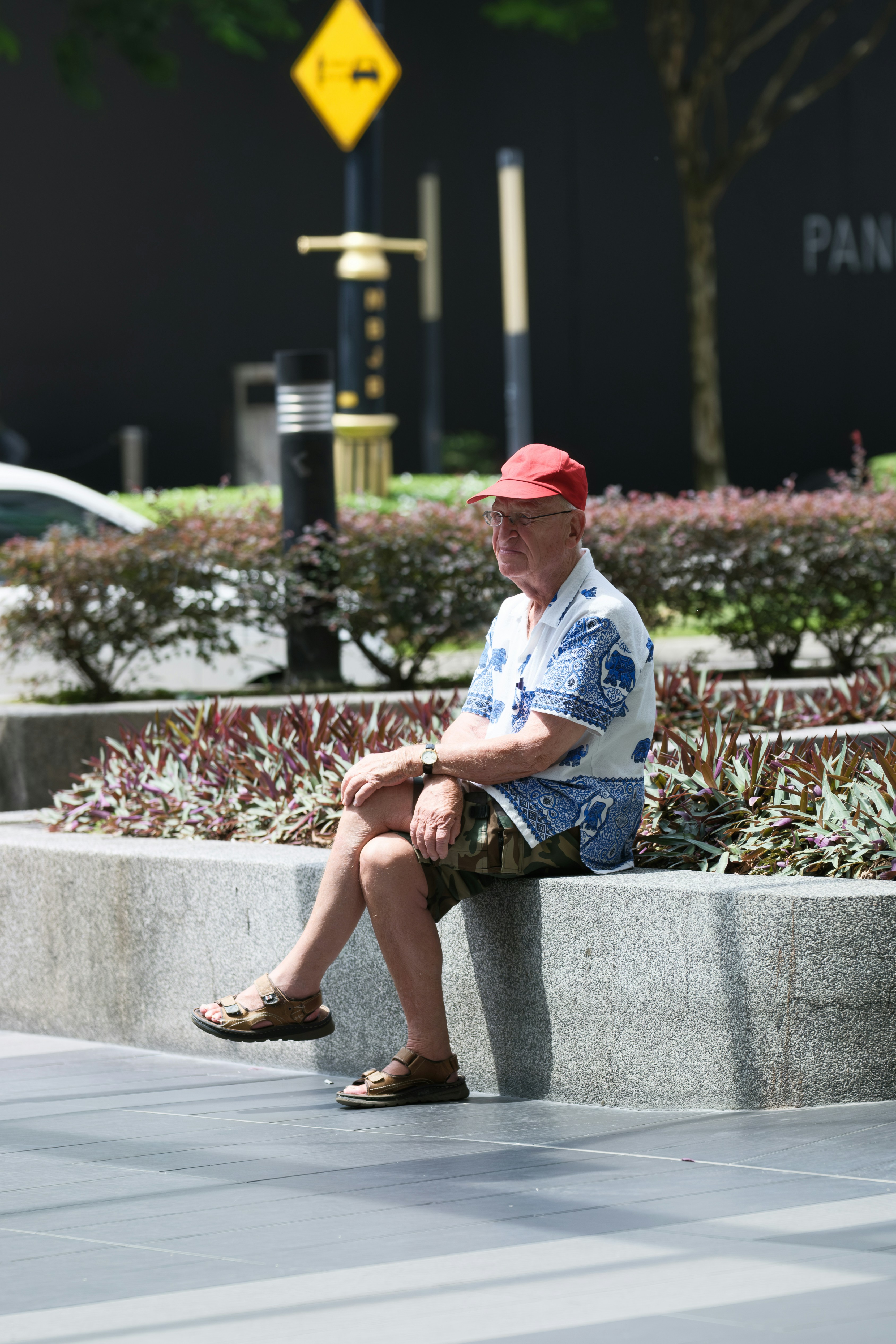 Elderly man in red cap sitting outdoors