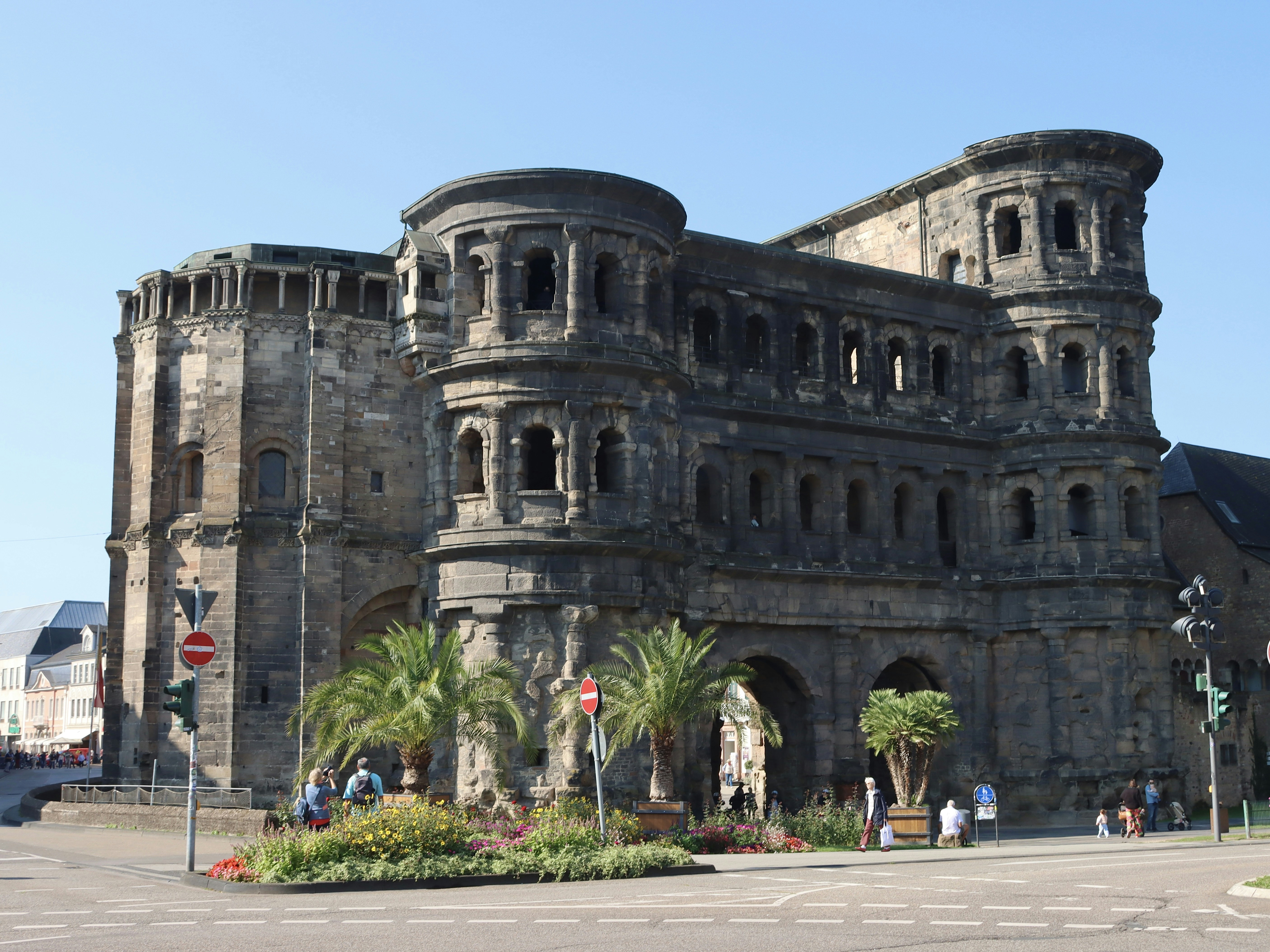 Ancient roman gate with palm trees and people