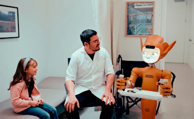 Doctor, girl, and robot in a medical room.