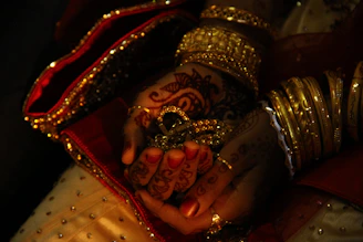 Bride's hands adorned with henna and gold jewelry.