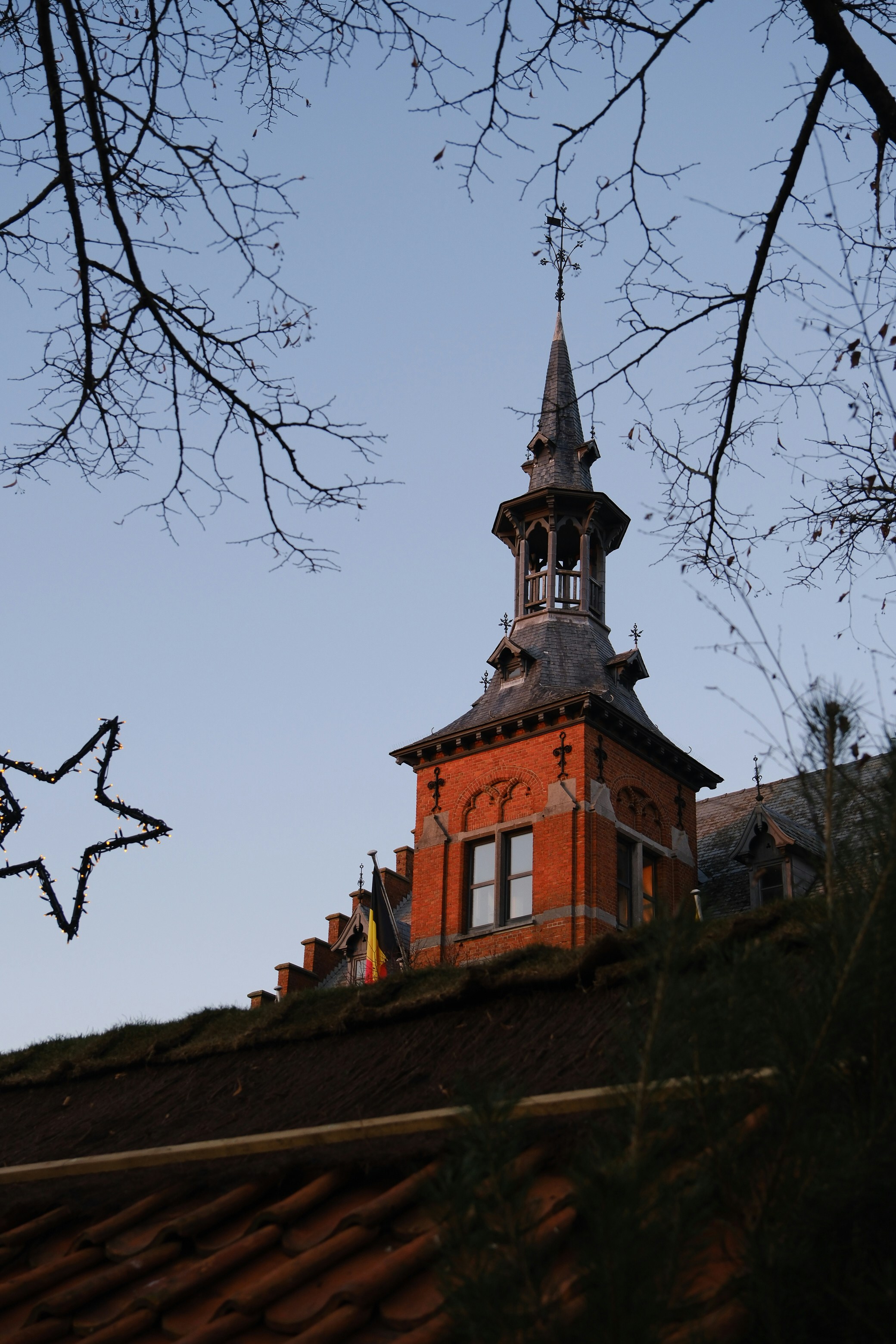 Brick tower with a spire against a clear sky.