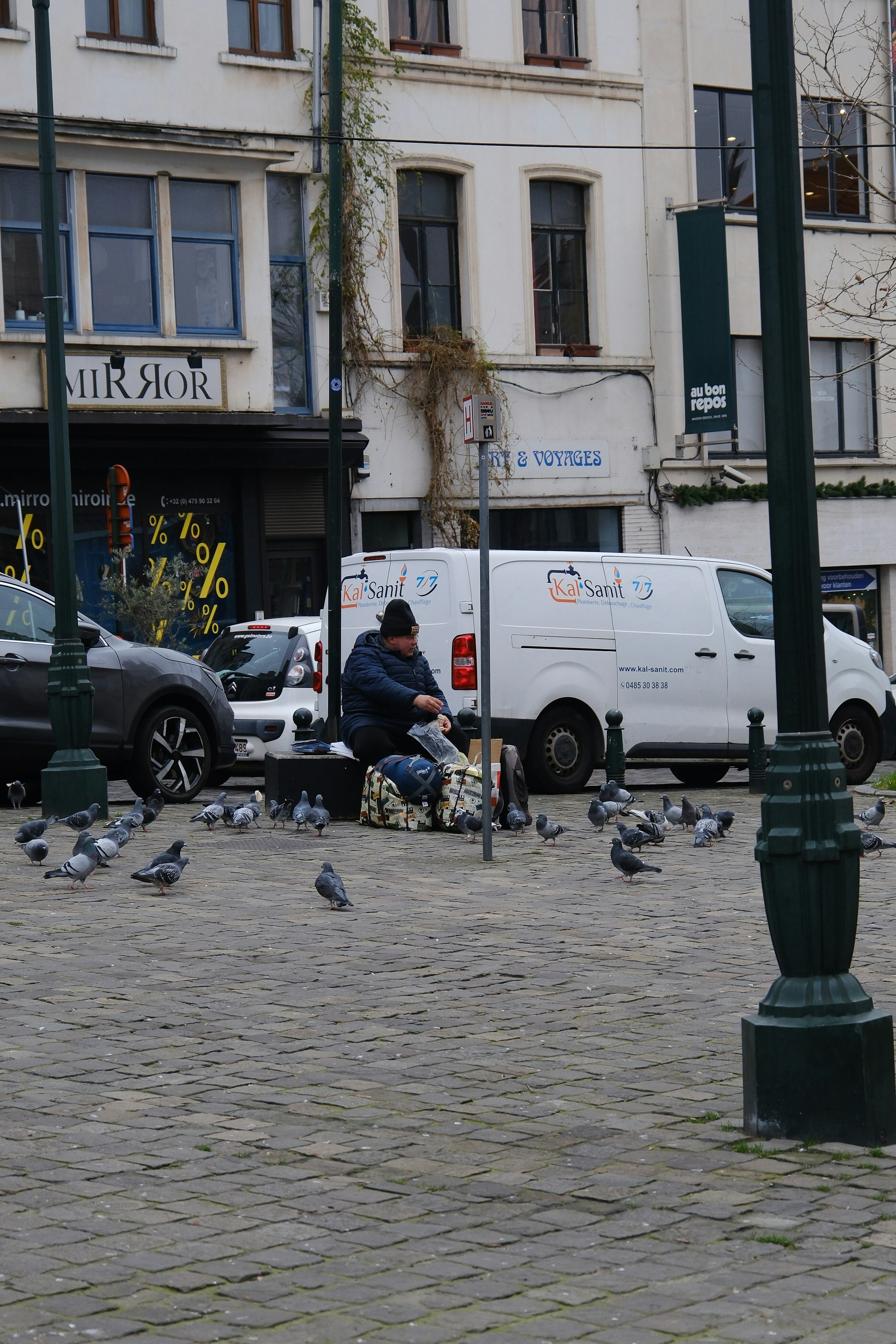 Man feeding pigeons in a city square