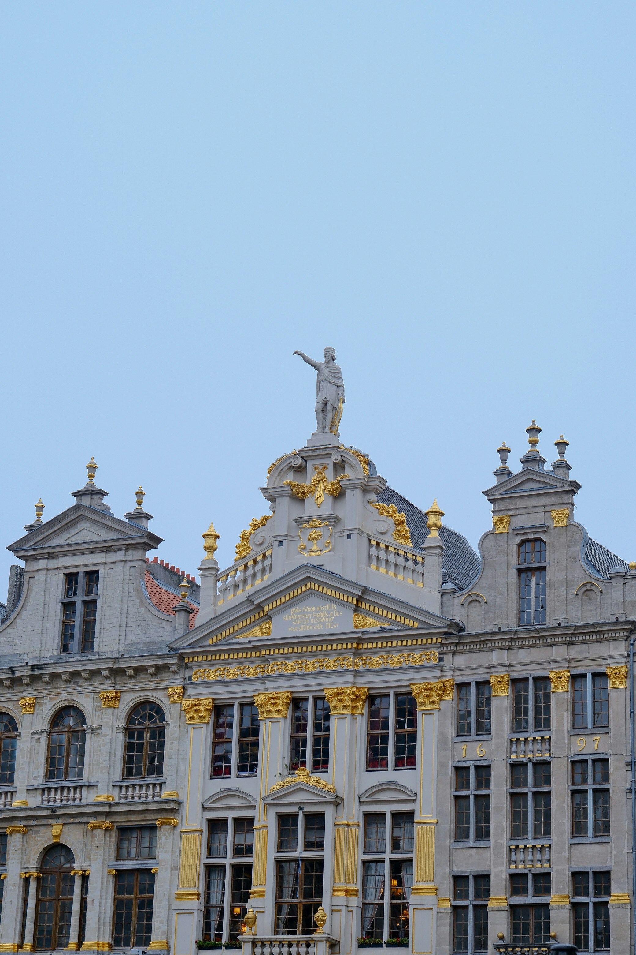Ornate buildings with a statue against a clear sky.