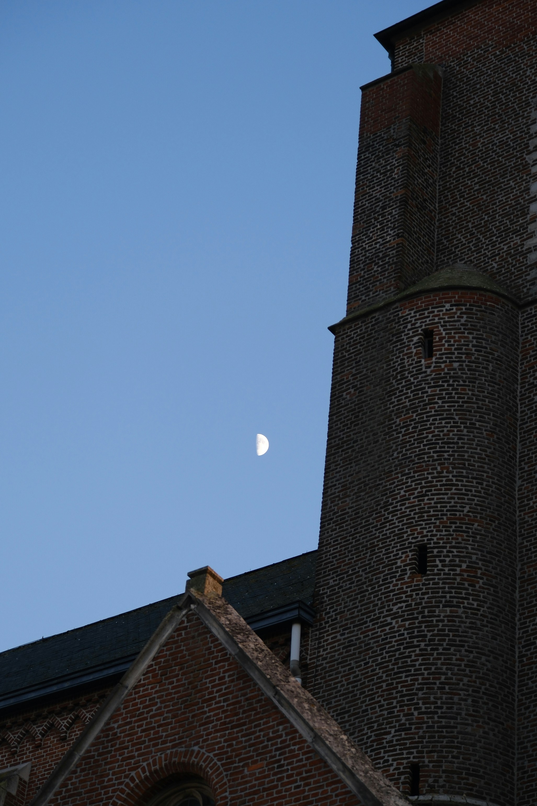 Half moon visible near a brick building