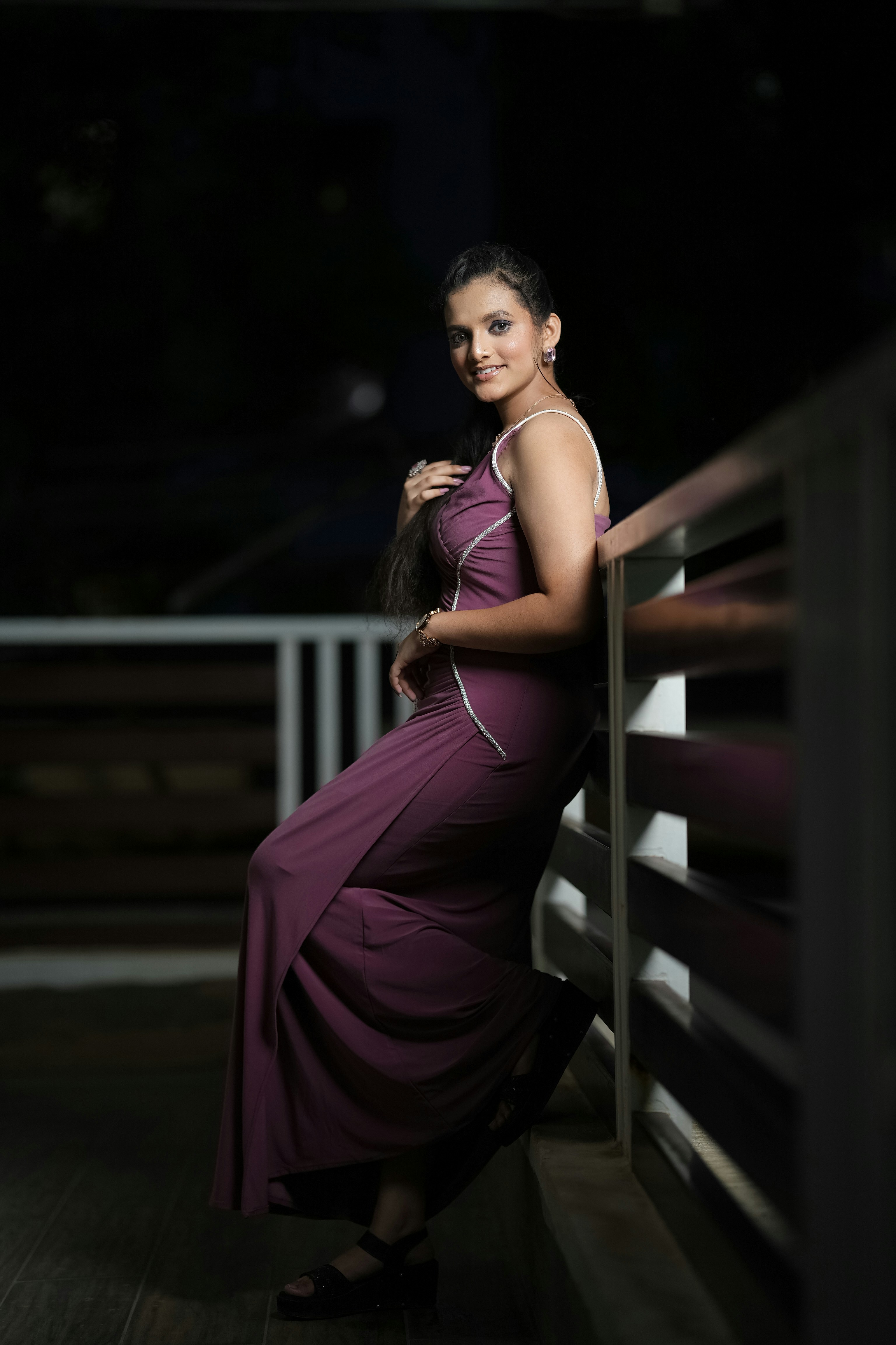 Frau in elegantem lila Kleid, lehnt sich an das Geländer