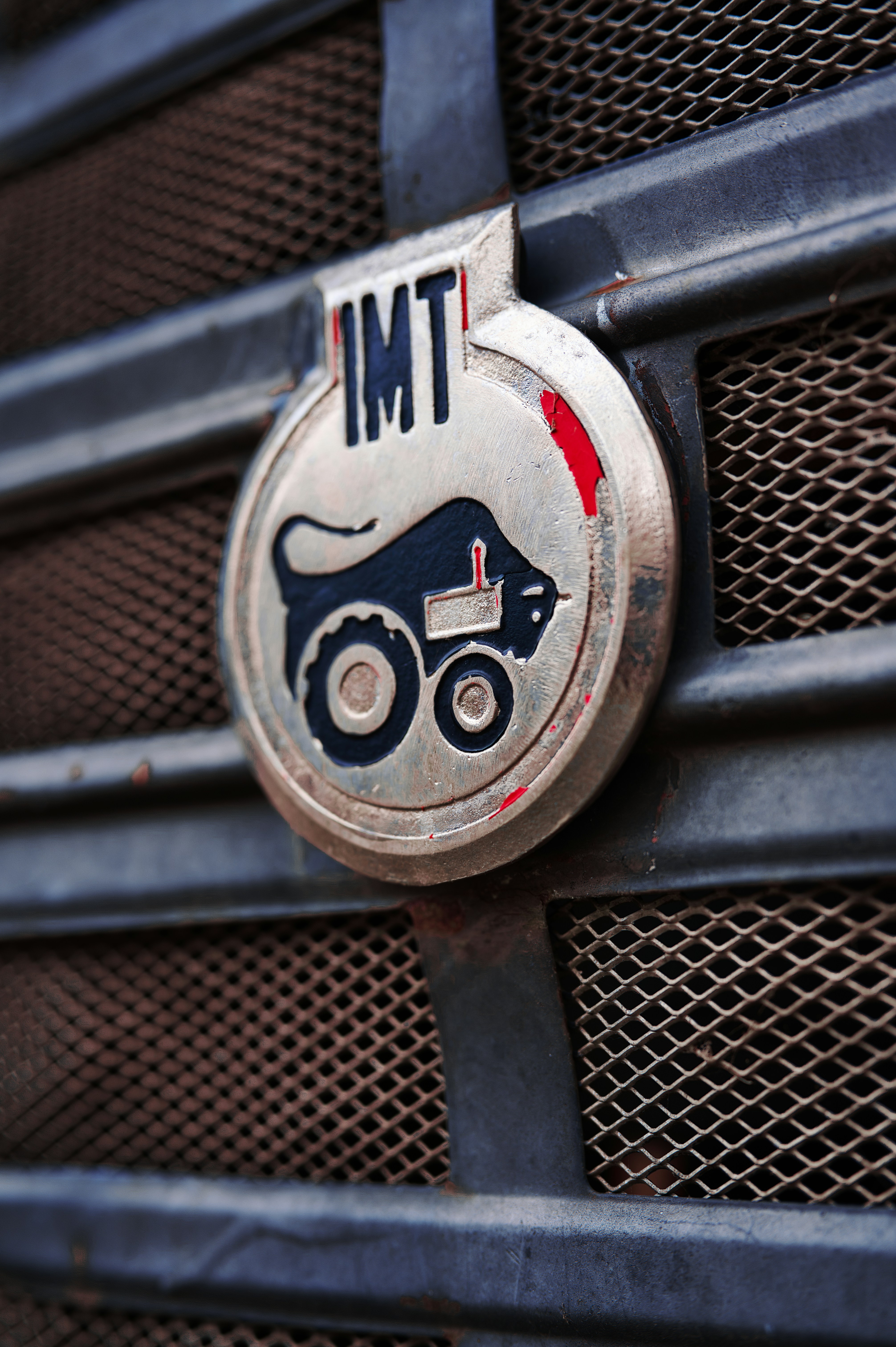 Close-up of an imt tractor emblem on a grille.