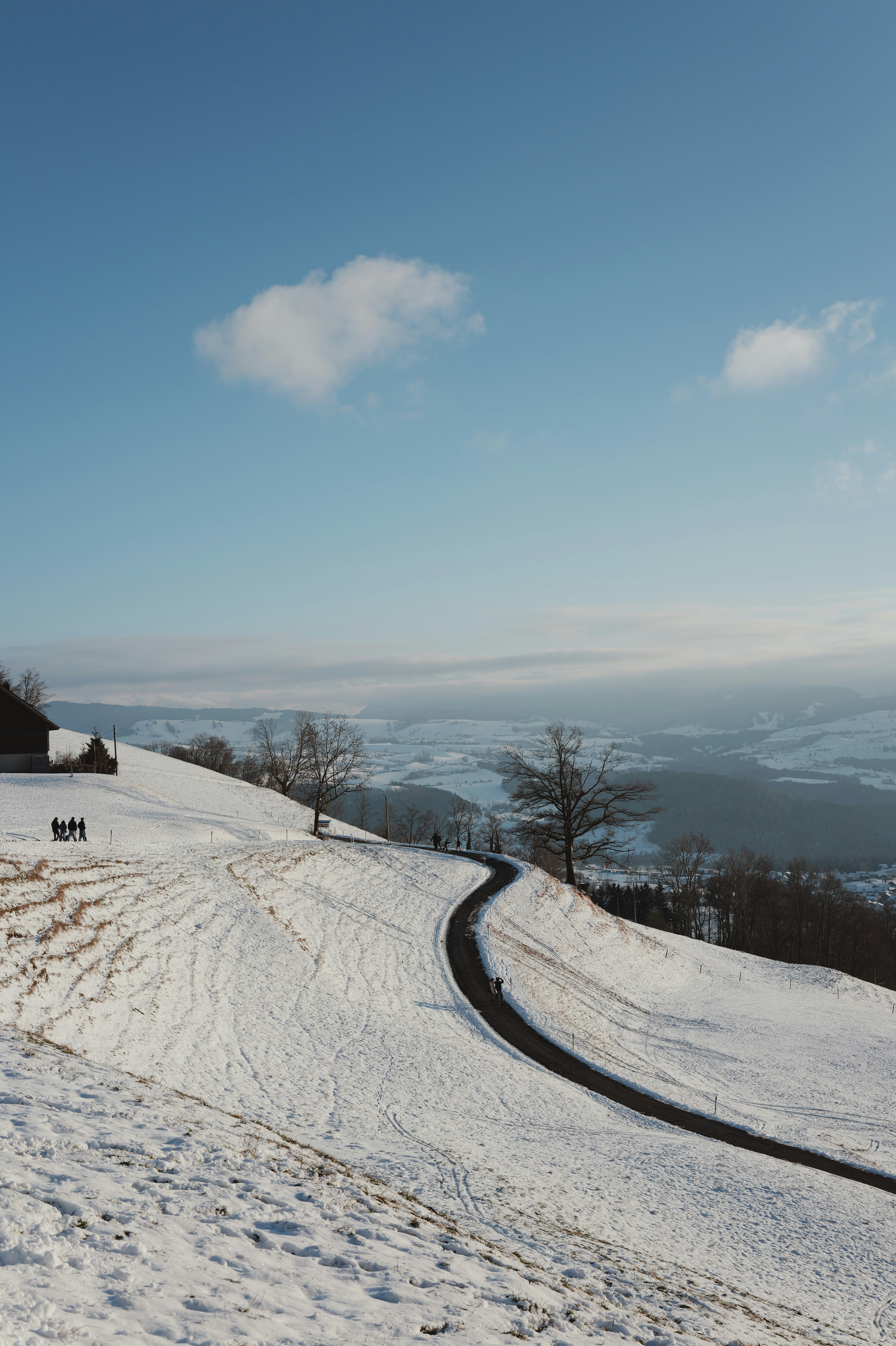Winding road through a snowy landscape under blue sky.