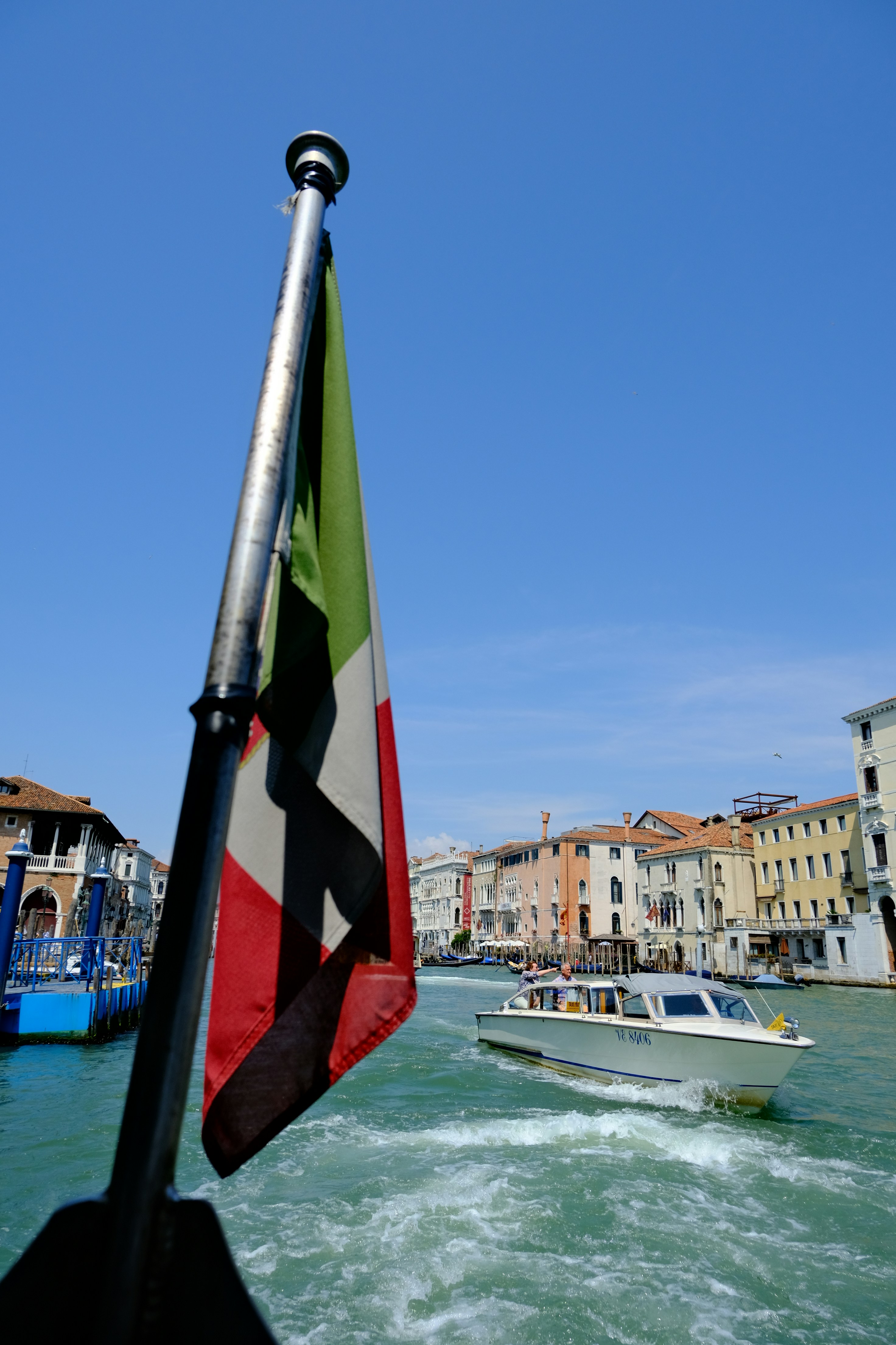 Italian flag waves near canal with boat