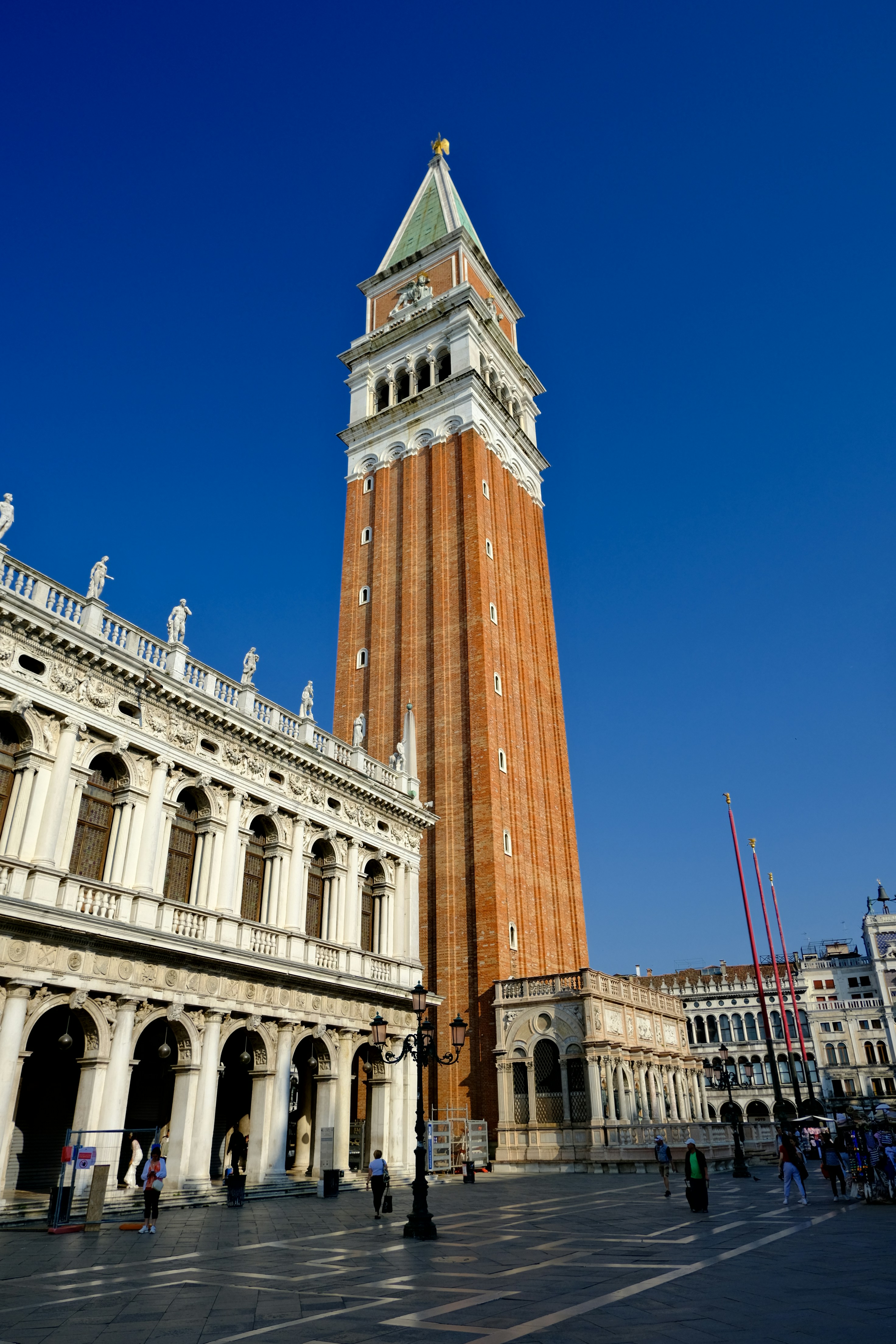 Tall brick bell tower with clock against blue sky