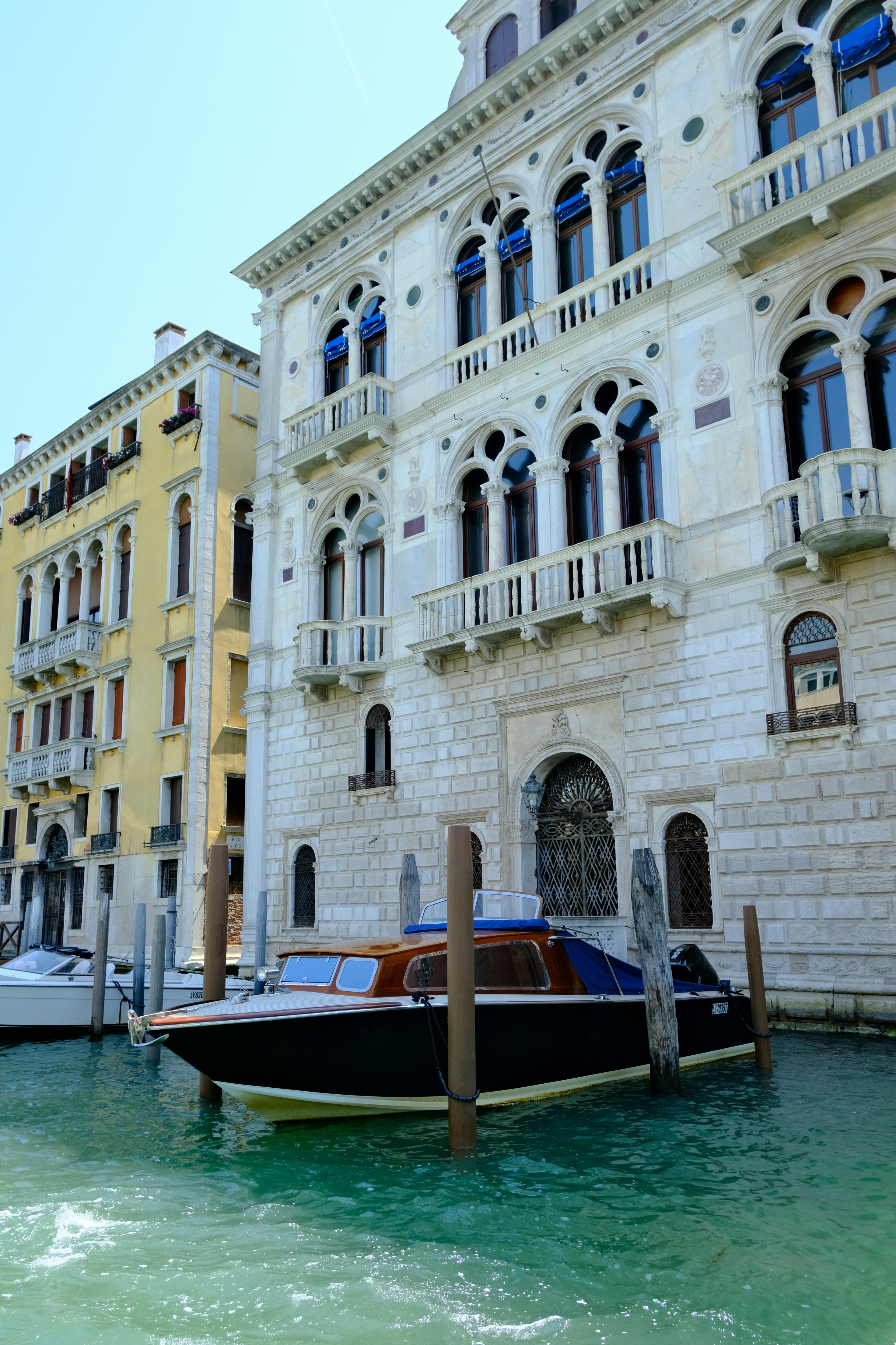 A boat docks beside ornate buildings along a canal.