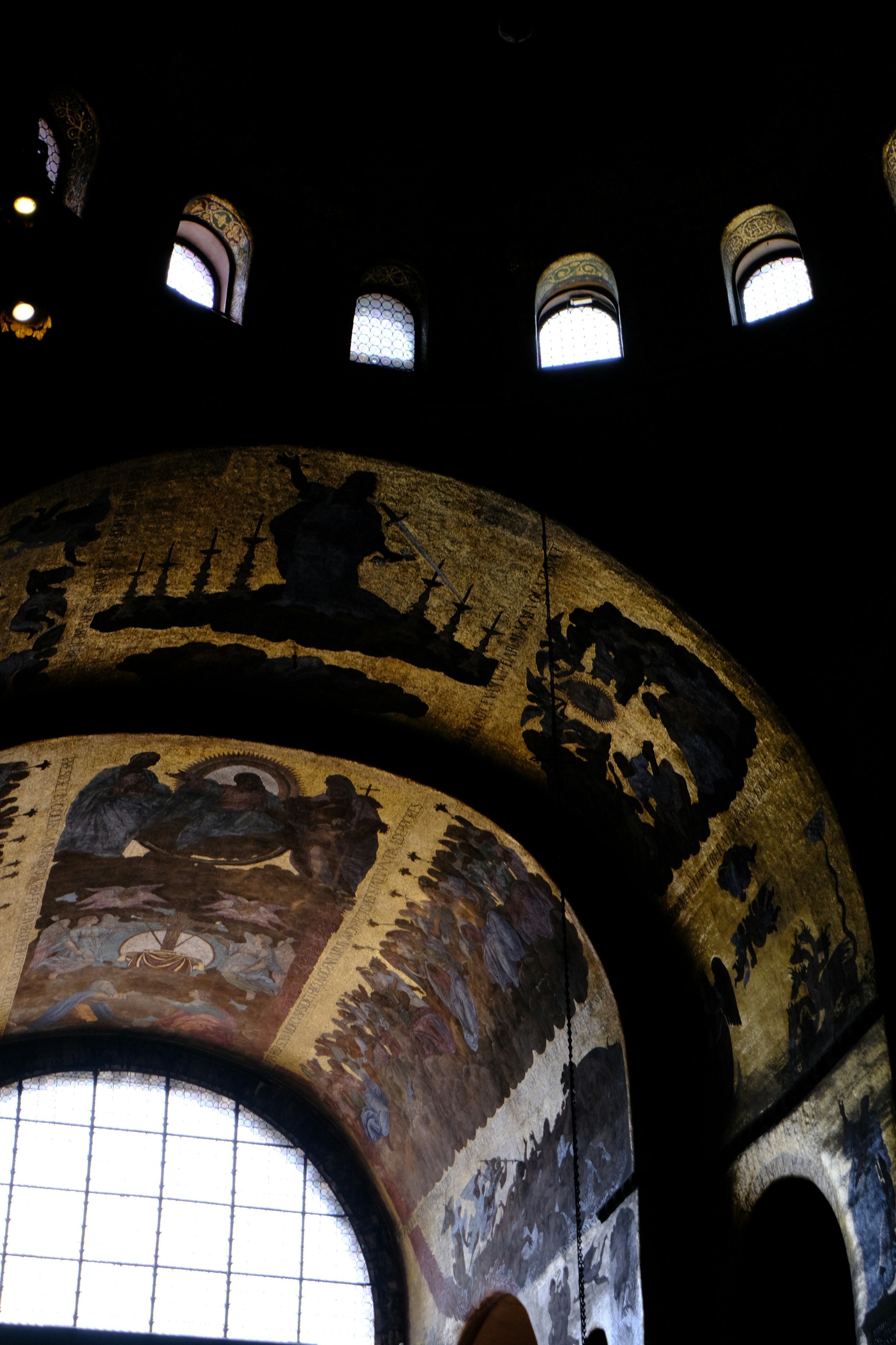Ancient mosaics adorn a domed interior with arched windows.