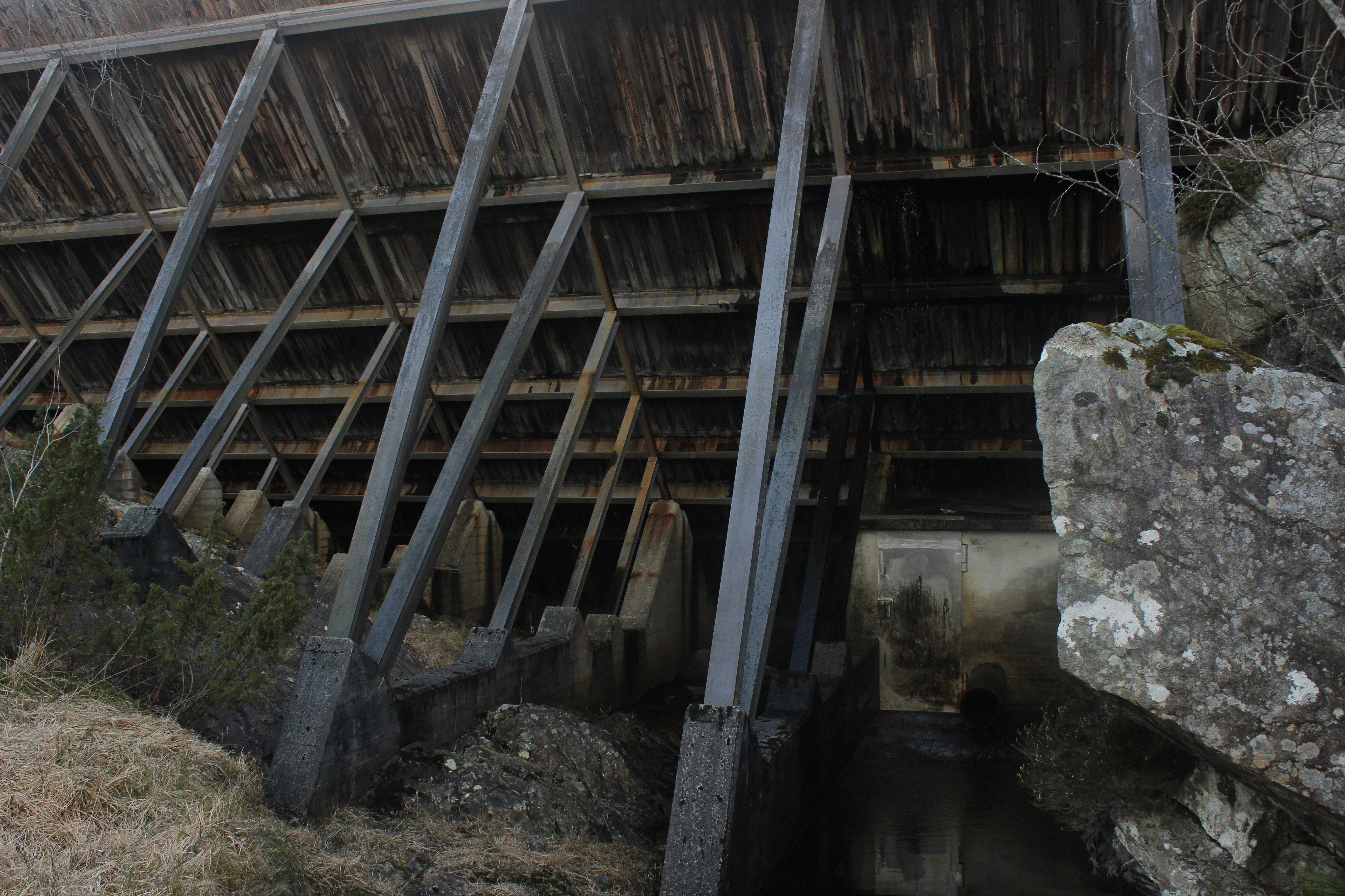 Old wooden structure with diagonal supports and rocks