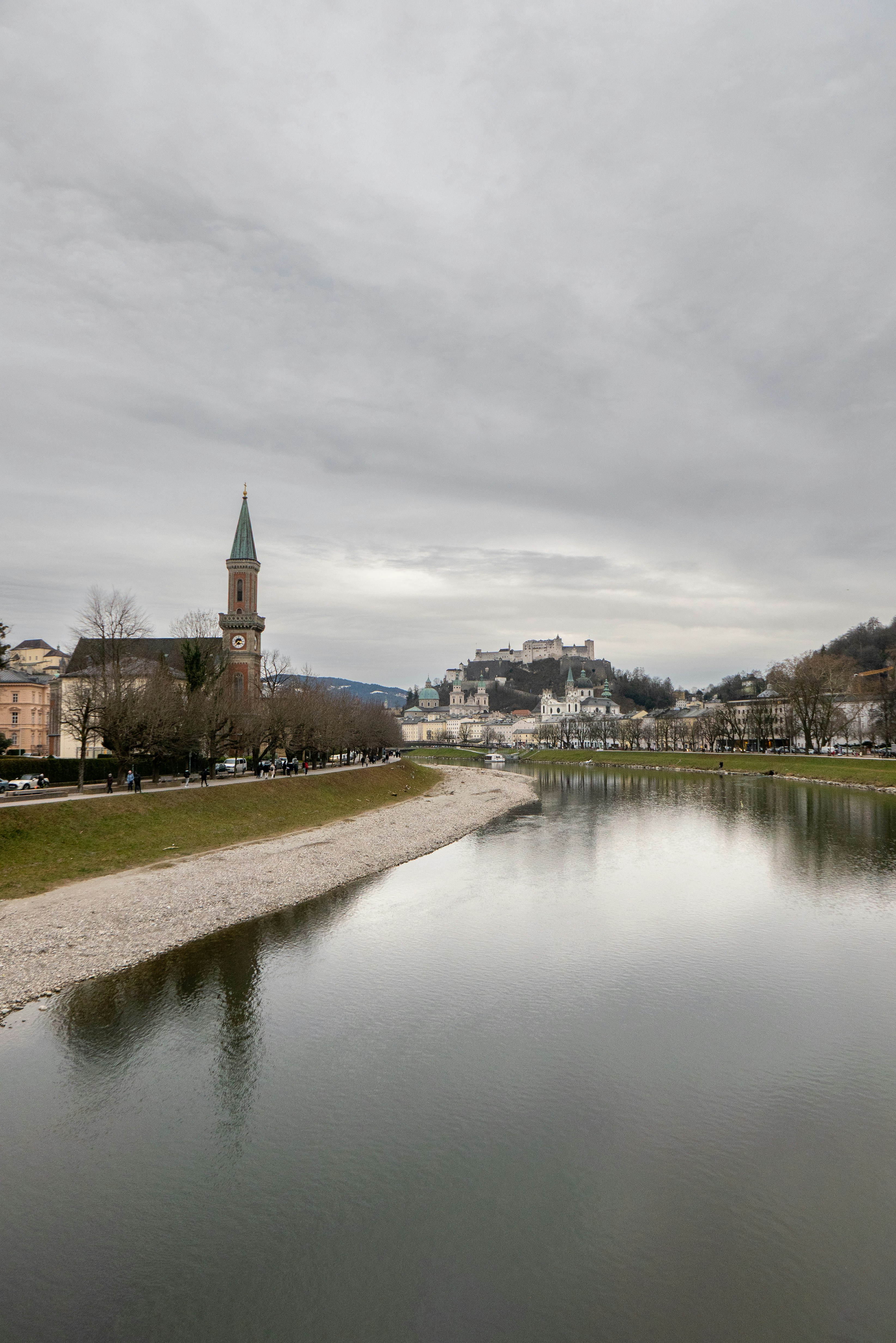 Río que fluye junto a un pueblo con un castillo en la colina.