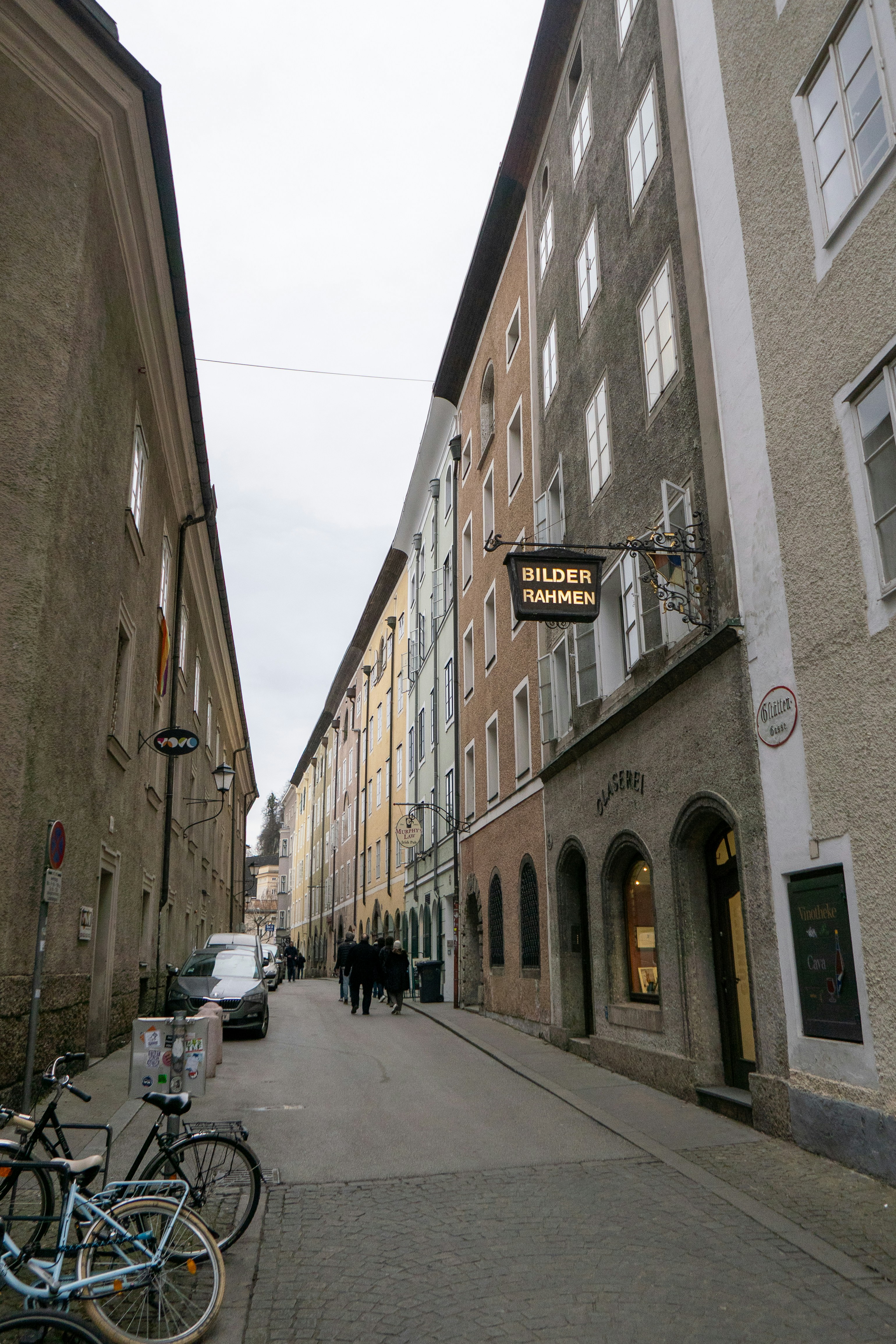 Calle europea estrecha con edificios y gente coloridos.