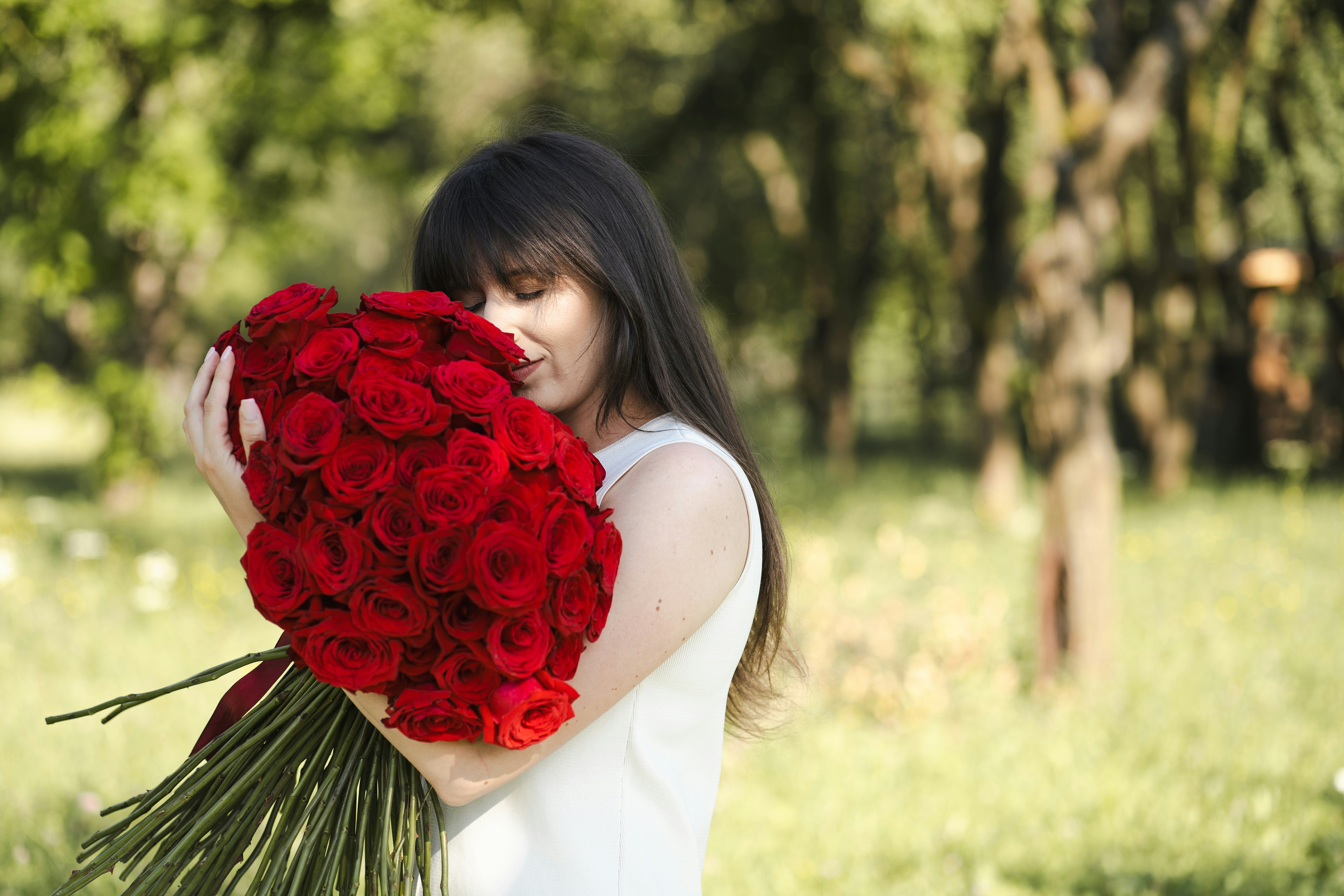 Mujer sosteniendo un gran ramo de rosas rojas