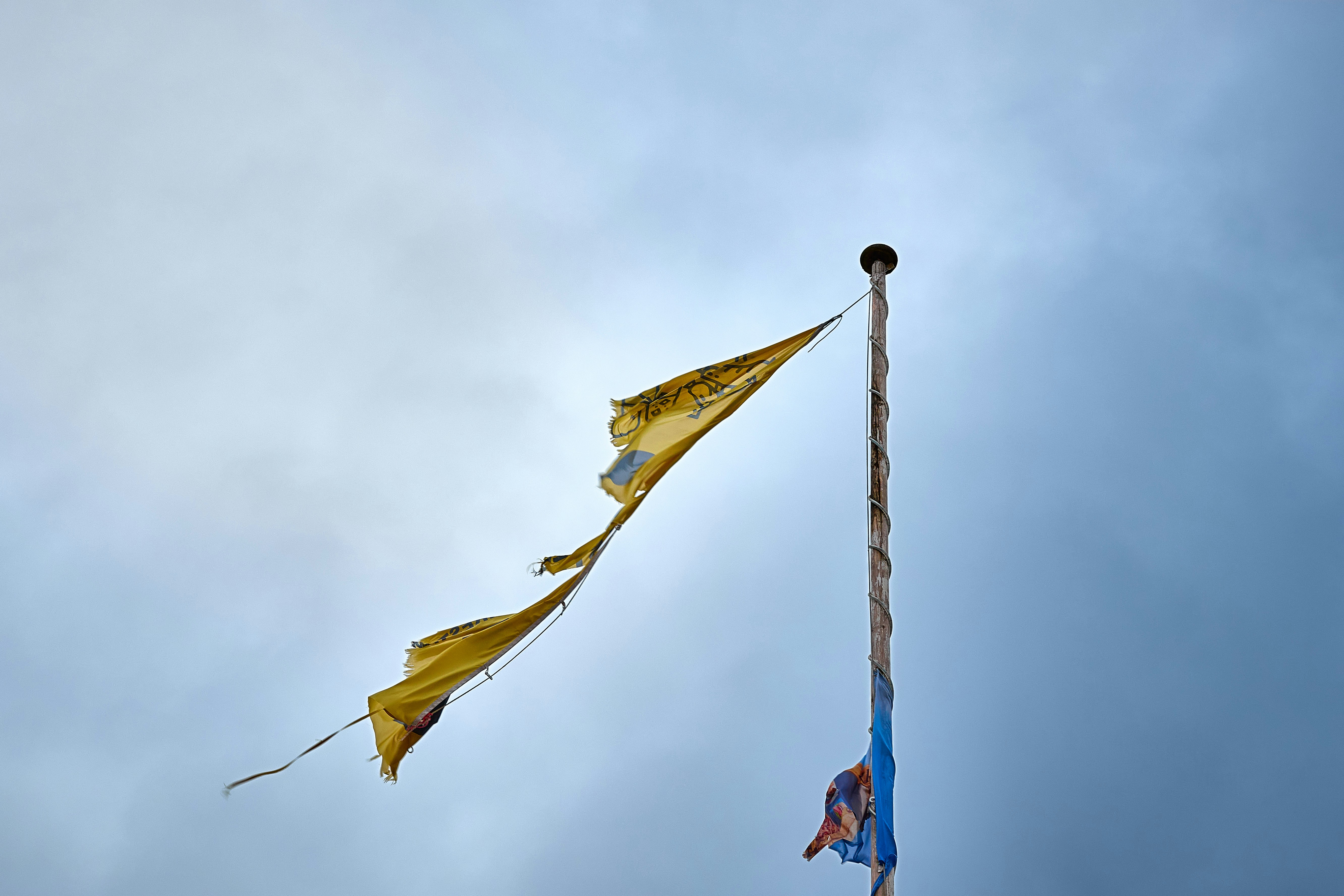 Tattered yellow flags against a cloudy sky