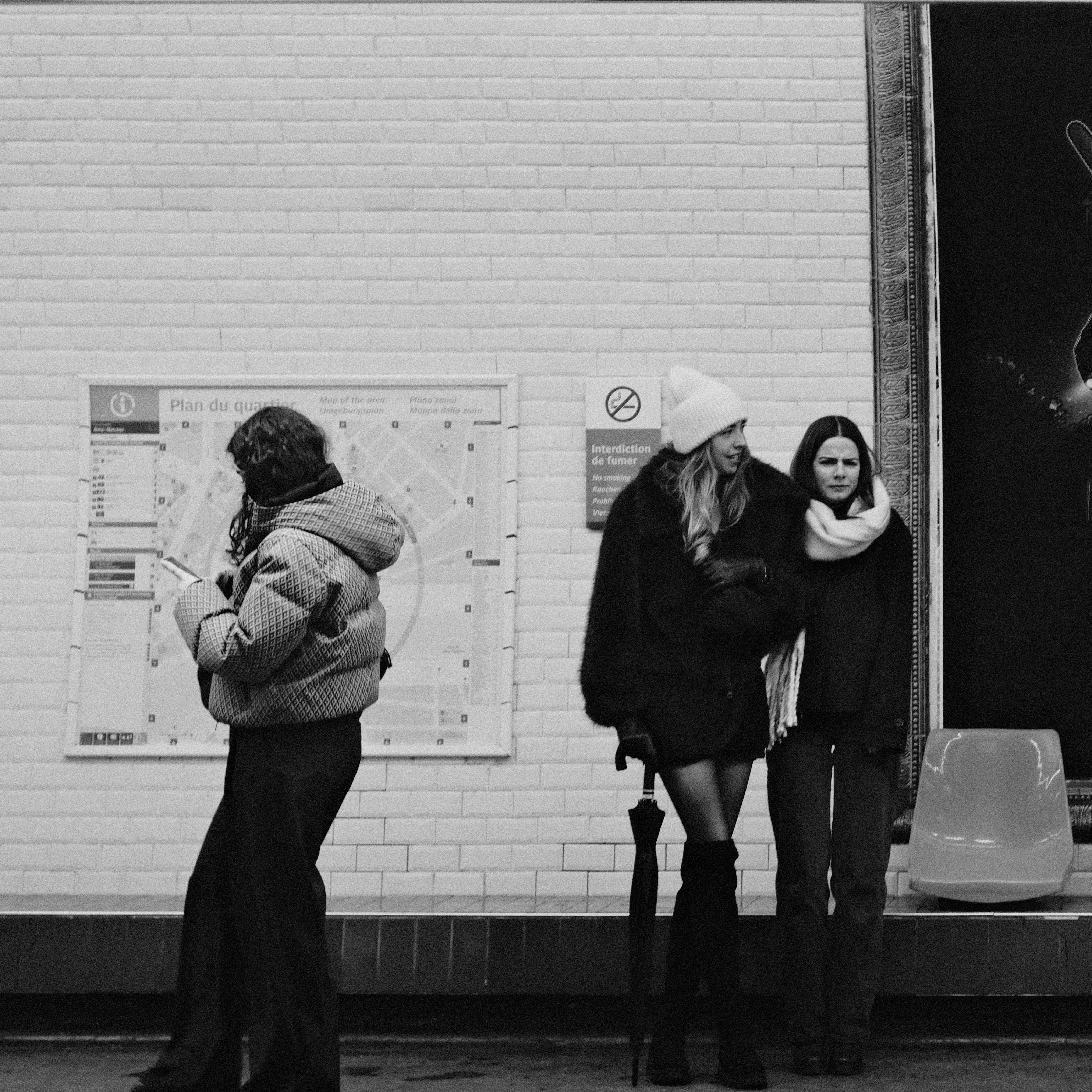 Two women stand at a subway station with map.