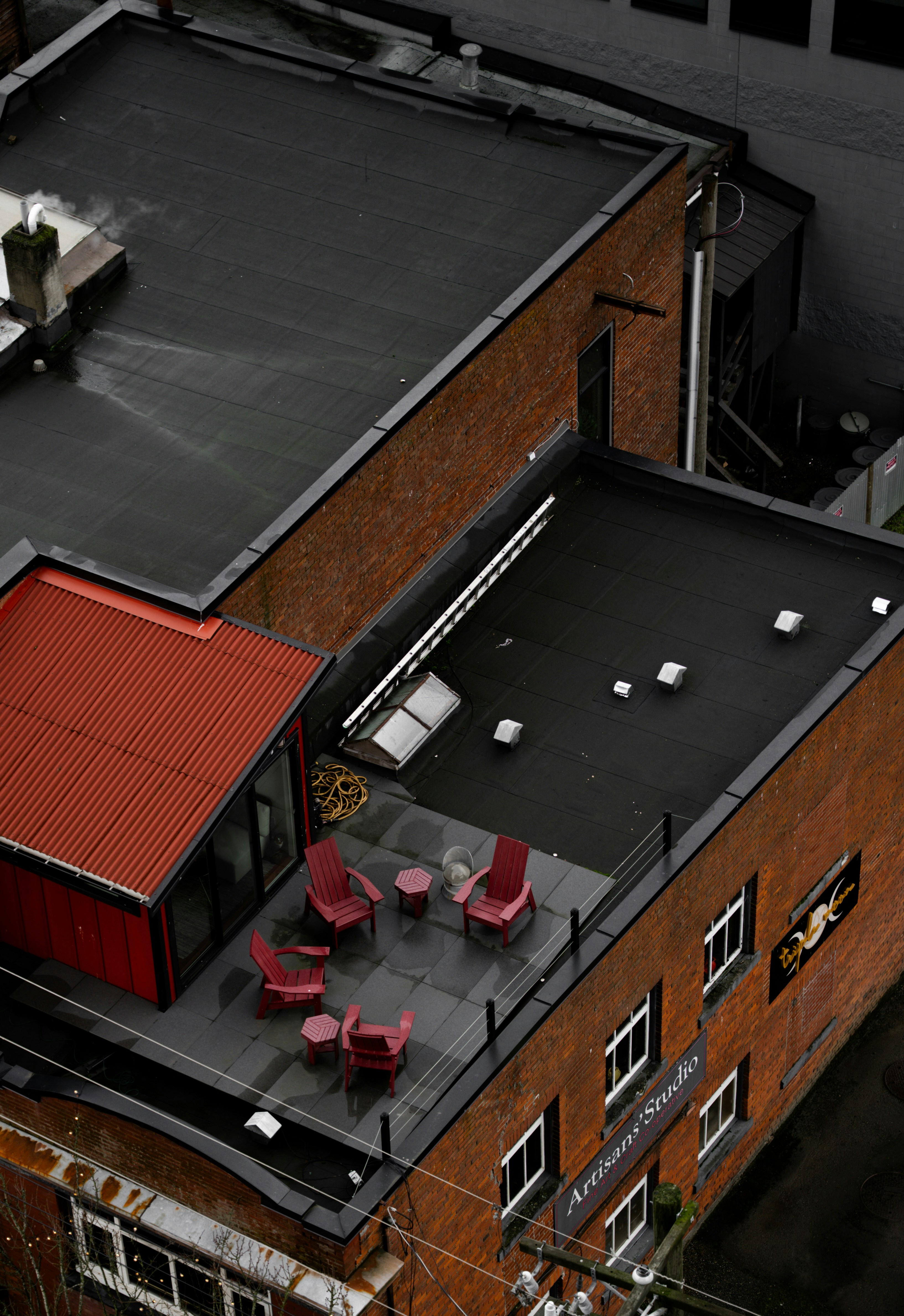 Rooftop patio with red chairs and tables.