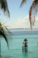 Lifeguard tower in turquoise ocean with distant city skyline.