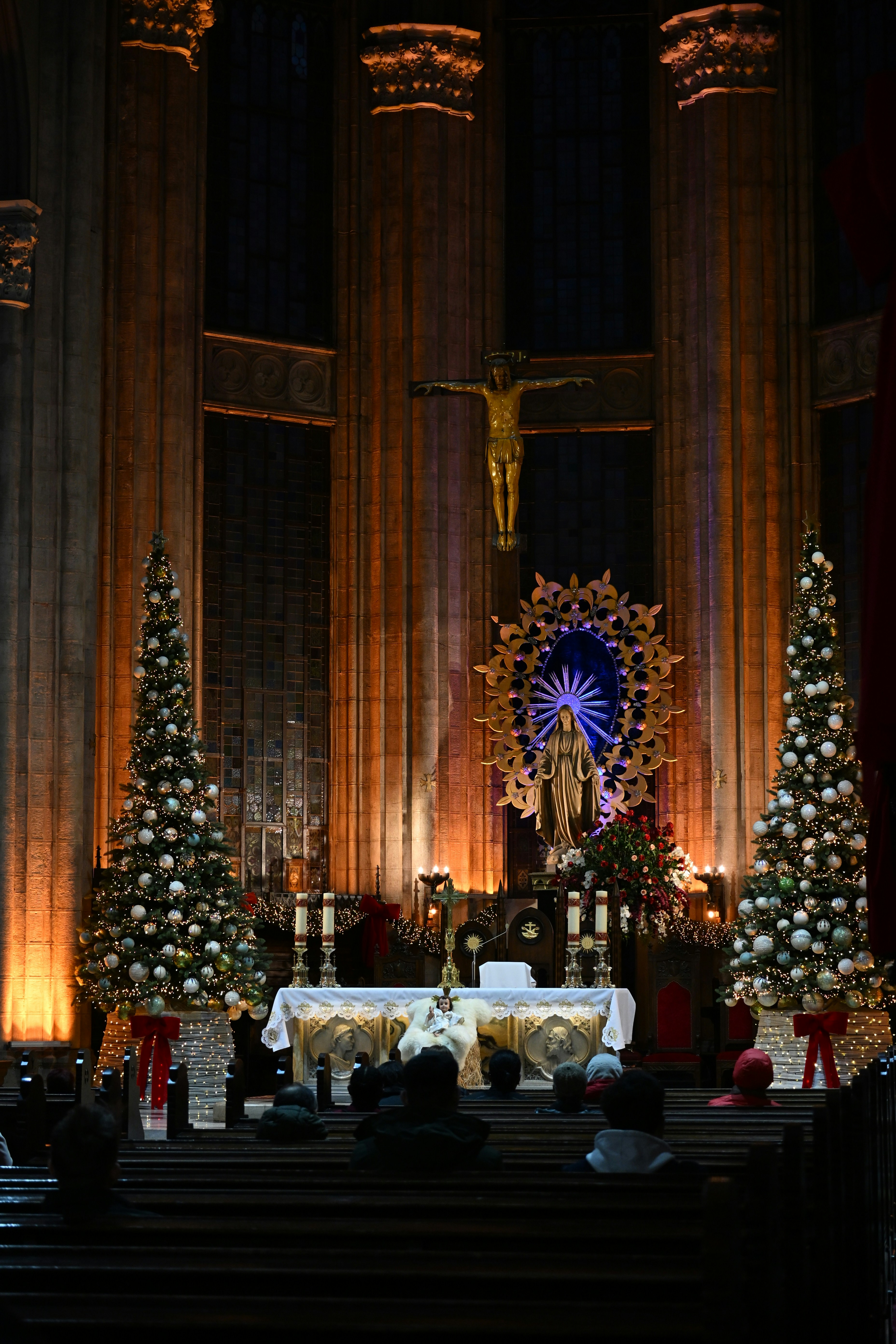 Christmas trees flank altar in dimly lit church