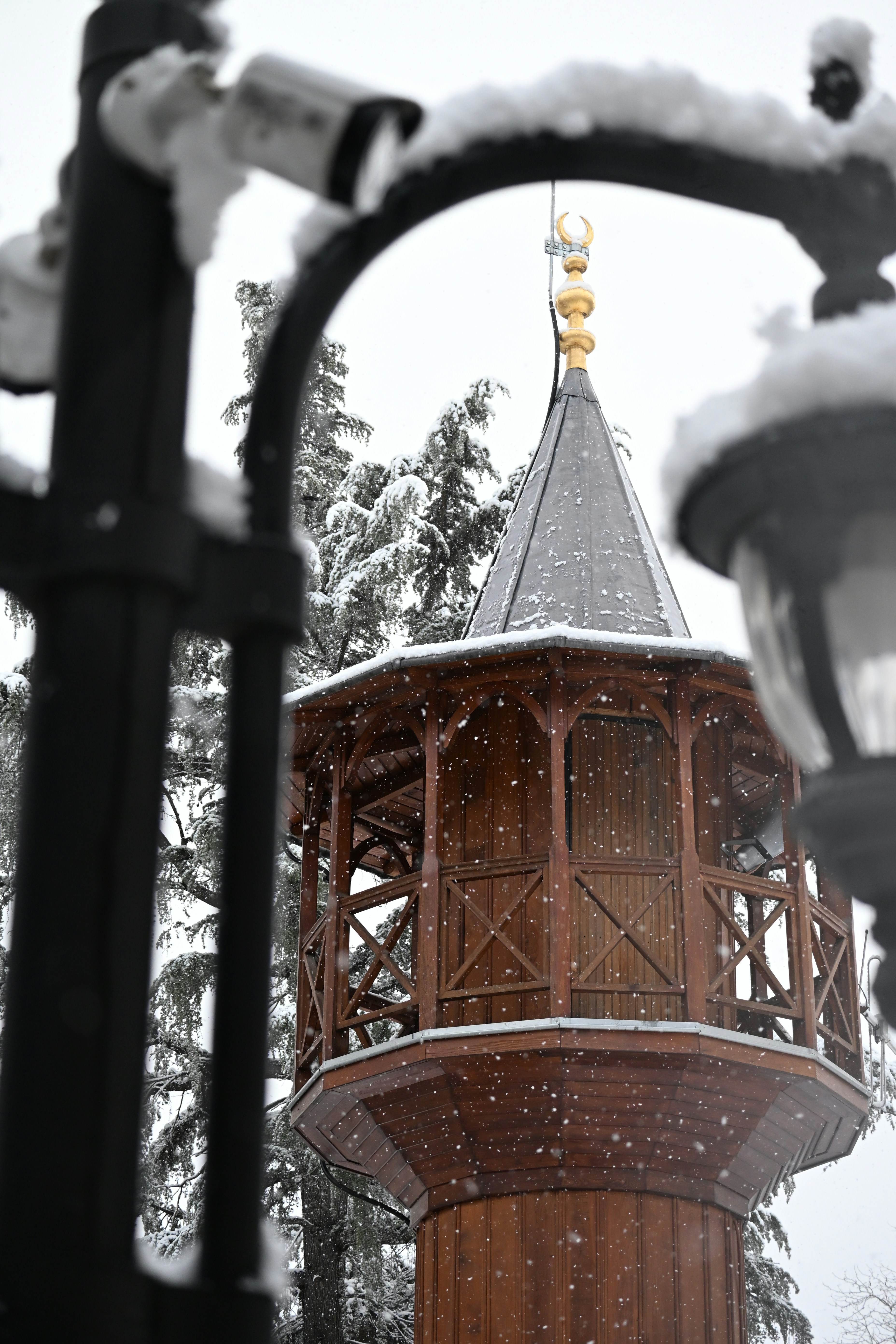 Wooden minaret with crescent moon in snowfall