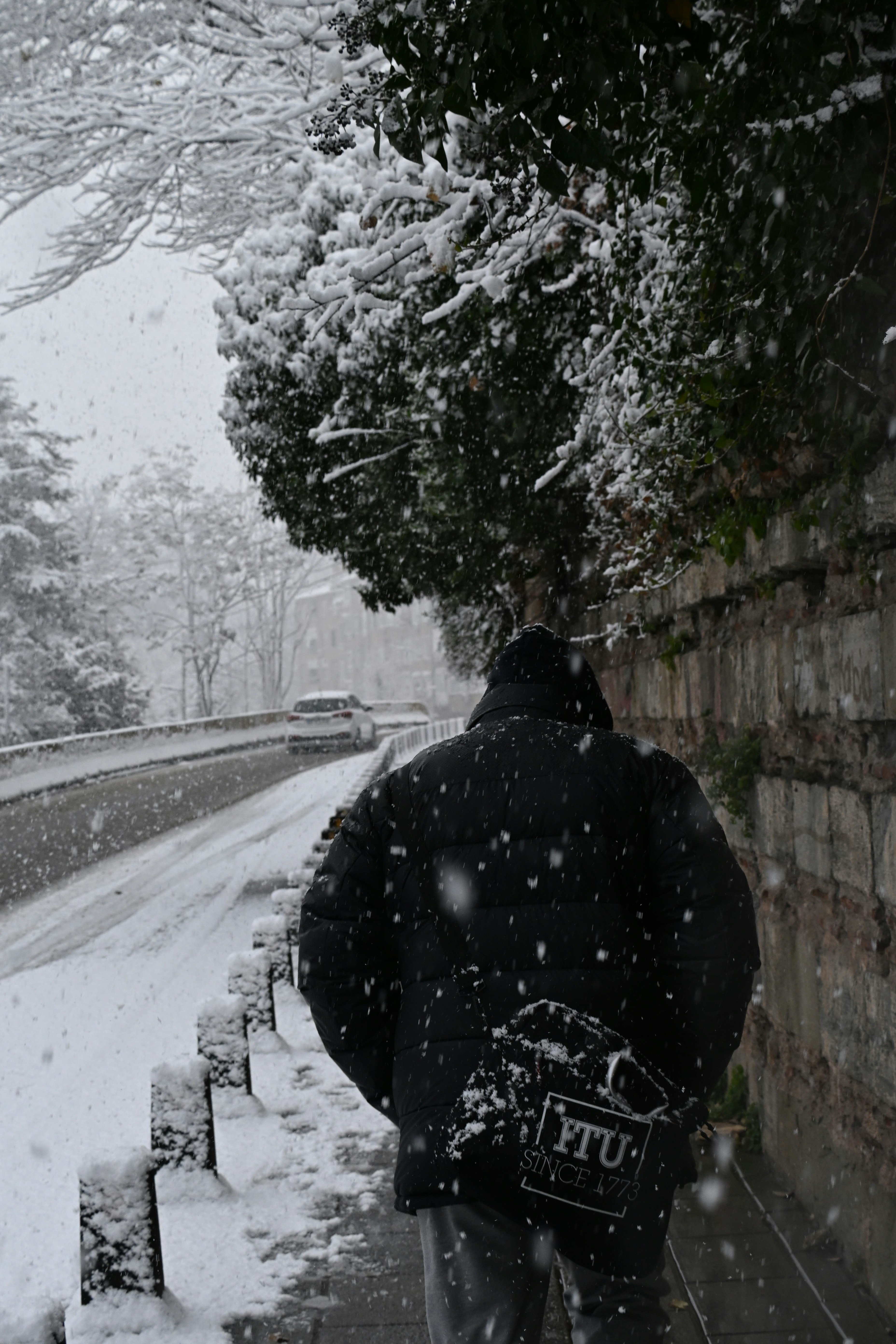 Person walking on a snowy path next to a road.