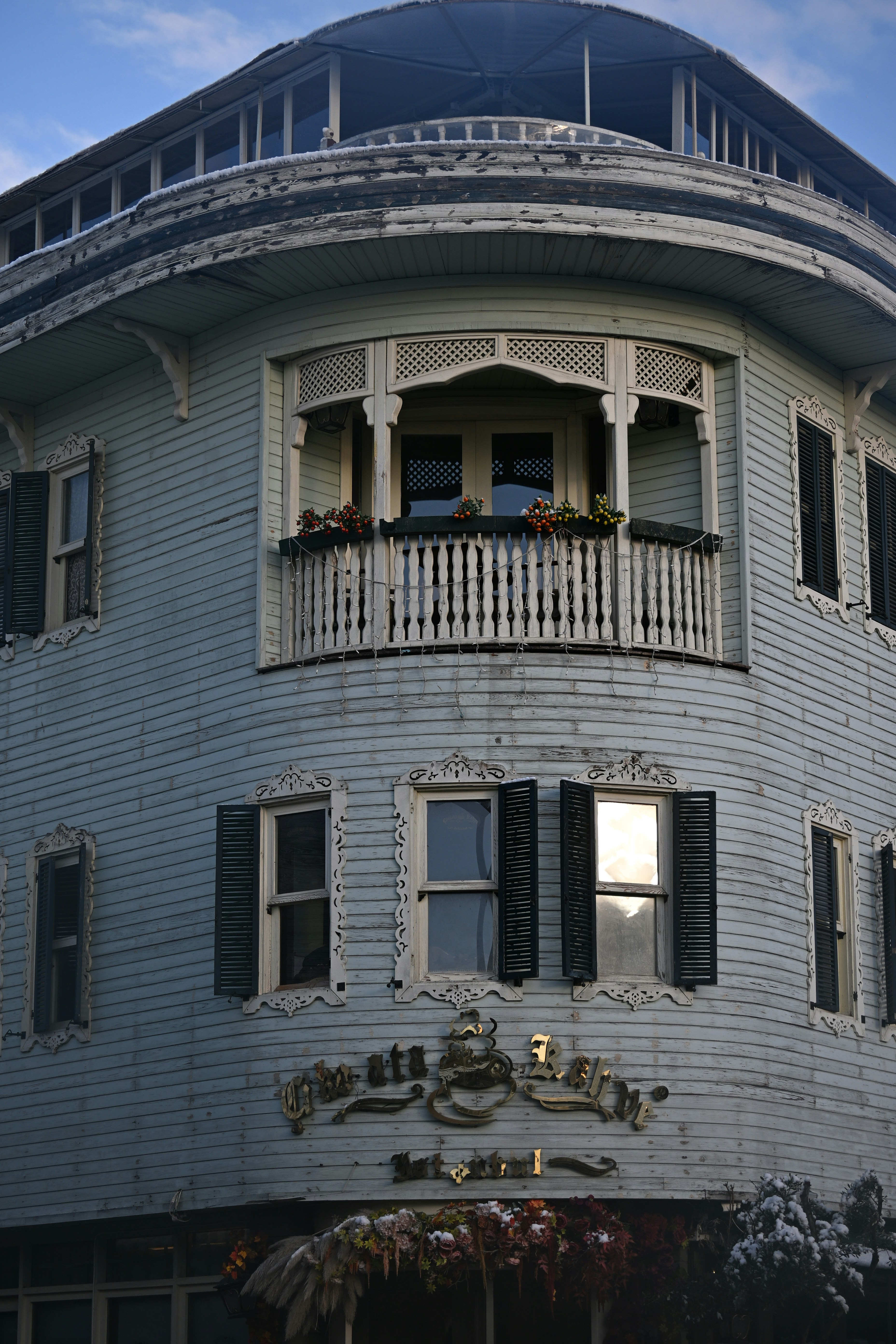 Light blue wooden building with ornate balcony and windows.