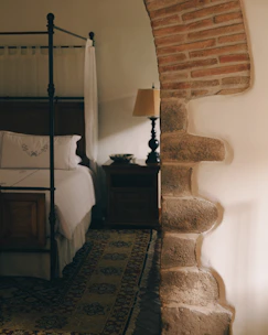 Four-poster bed with bedside table and lamp.