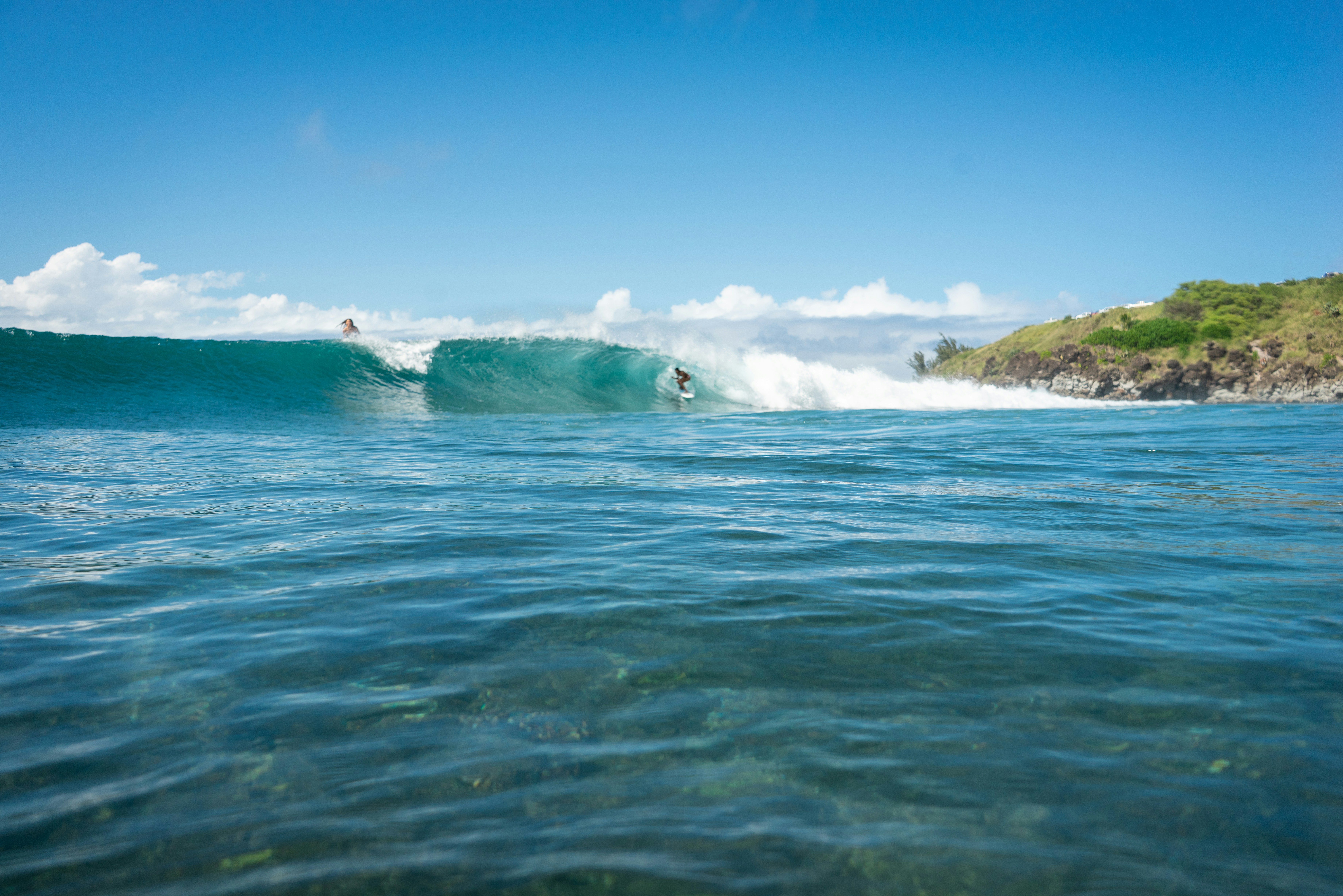 Surfer riding a breaking wave on a sunny day.