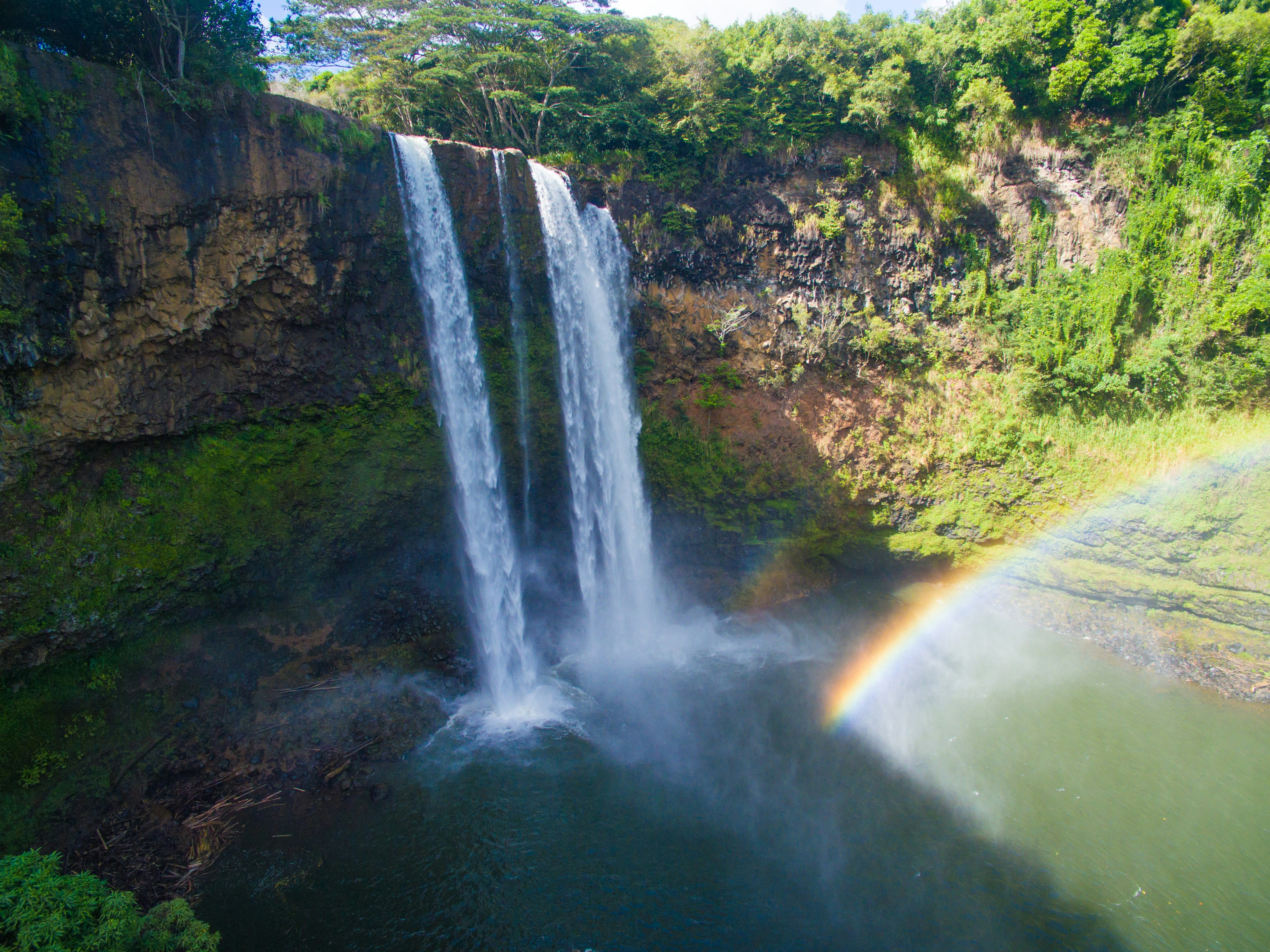 Waterfall cascading into a pool with a rainbow.