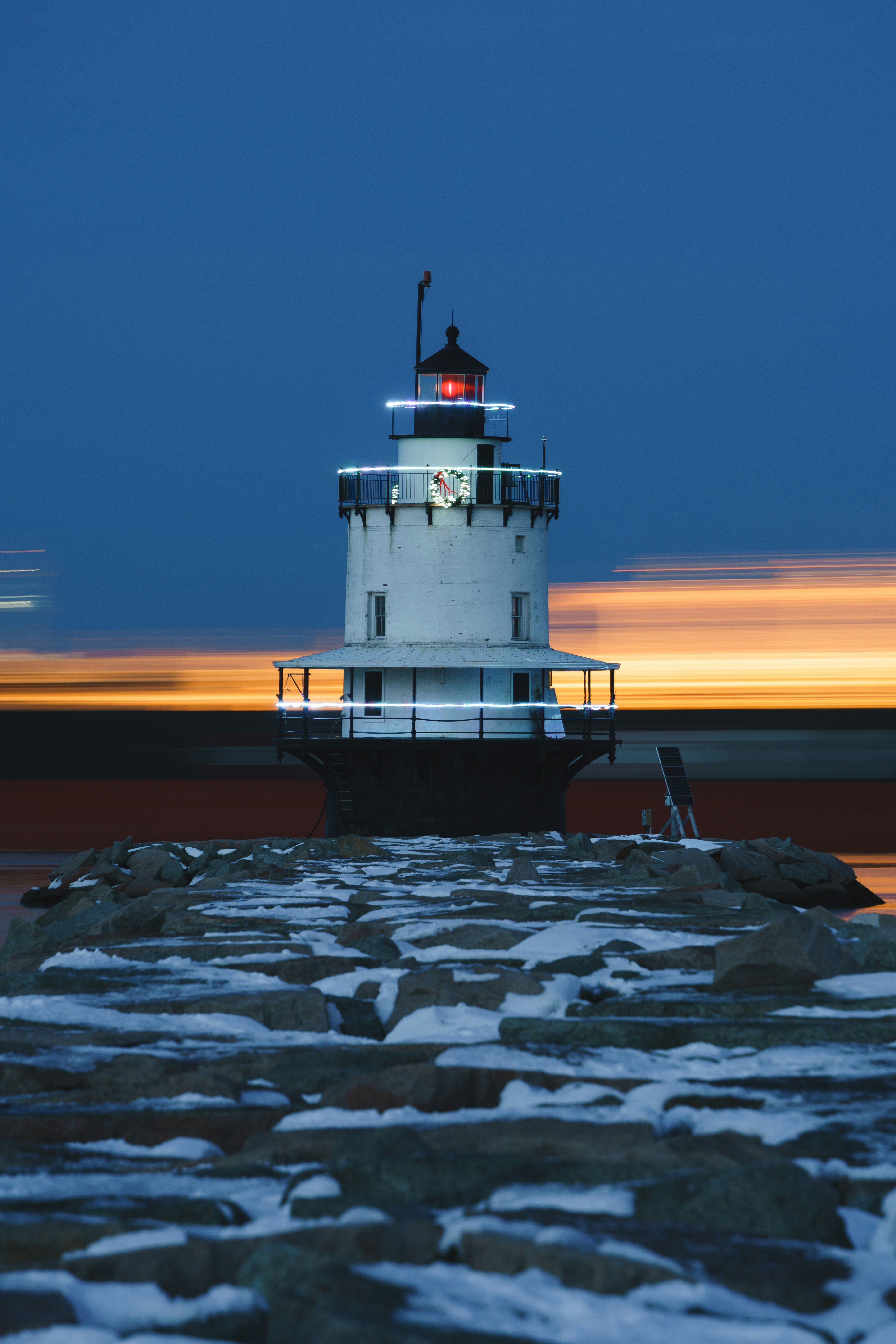Farol branco com luz vermelha ao entardecer
