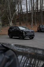 A black cadillac suv parked in a lot.