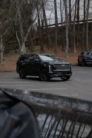 A black cadillac suv parked in a lot.