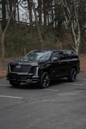 A black cadillac escalade parked in a lot.